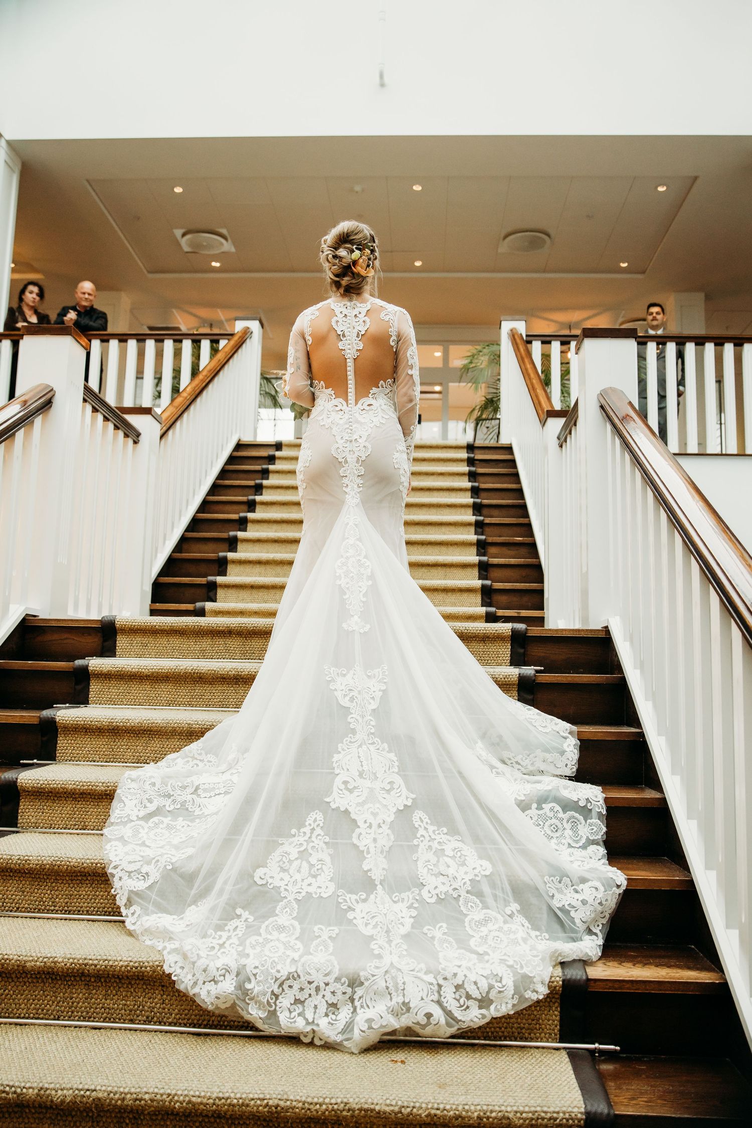 Wedding dress train with intricate lace details displayed on wooden stairs.