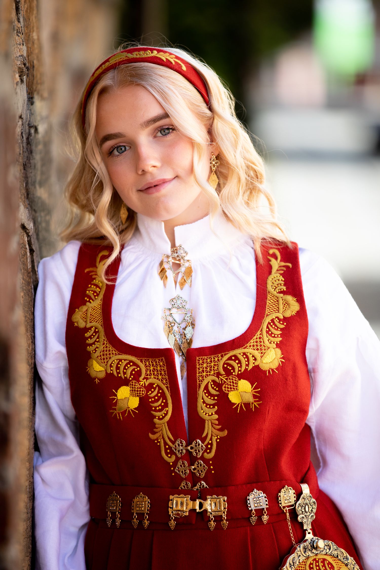 Traditional Norwegian folk dress with ornate gold embroidery and white blouse.