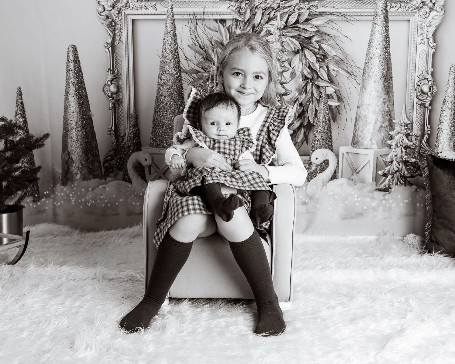 Winter themed studio portrait with snowy decorative trees and ornate frame backdrop.