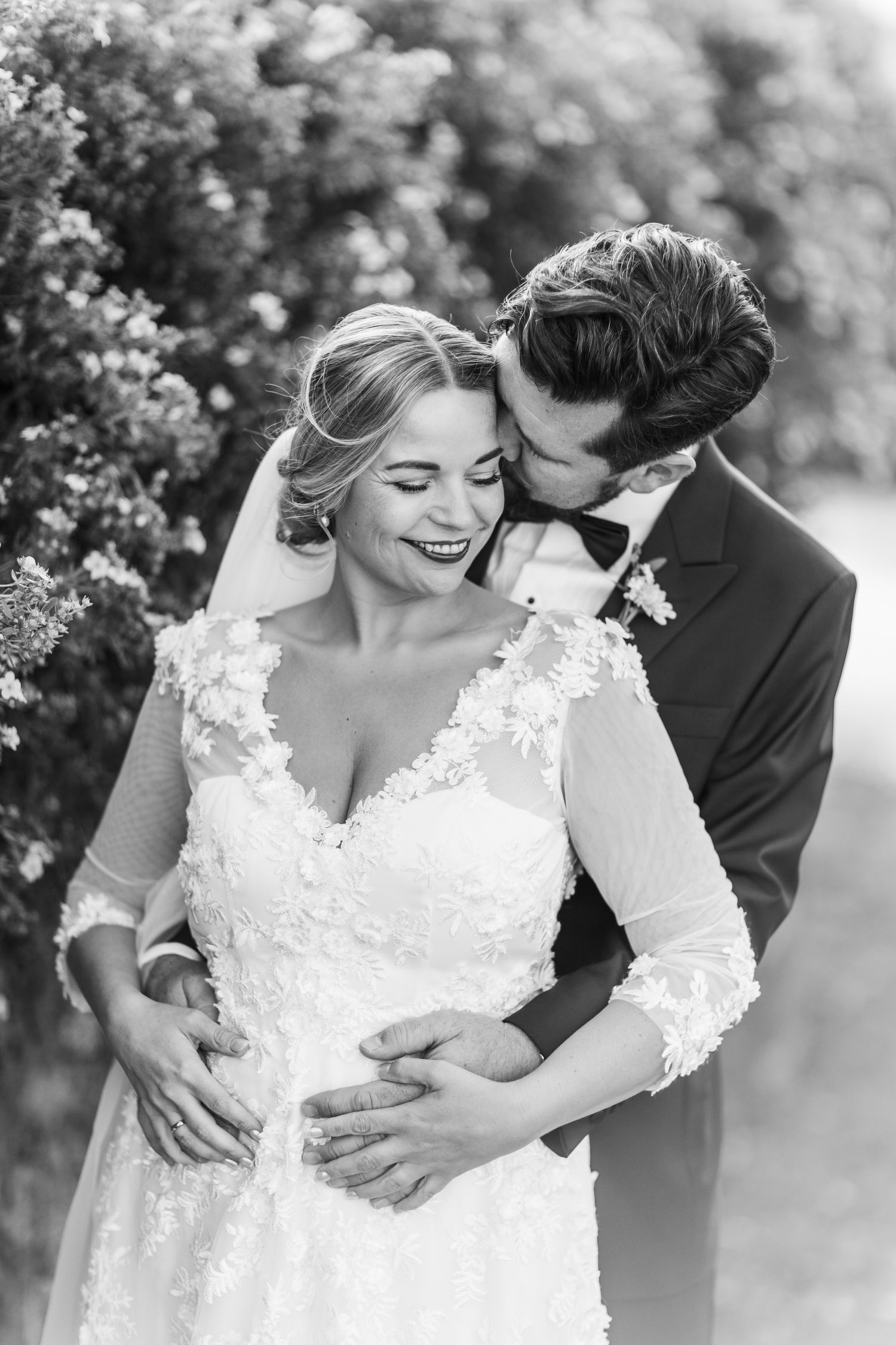 Black and white intimate wedding photo of couple sharing tender moment.