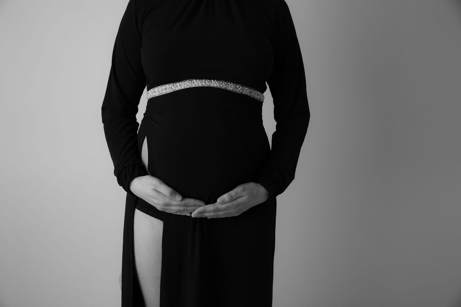 Stemningsfull gravidfotografering i Østfold: Detaljbilde av gravid mage i sort-hvitt.