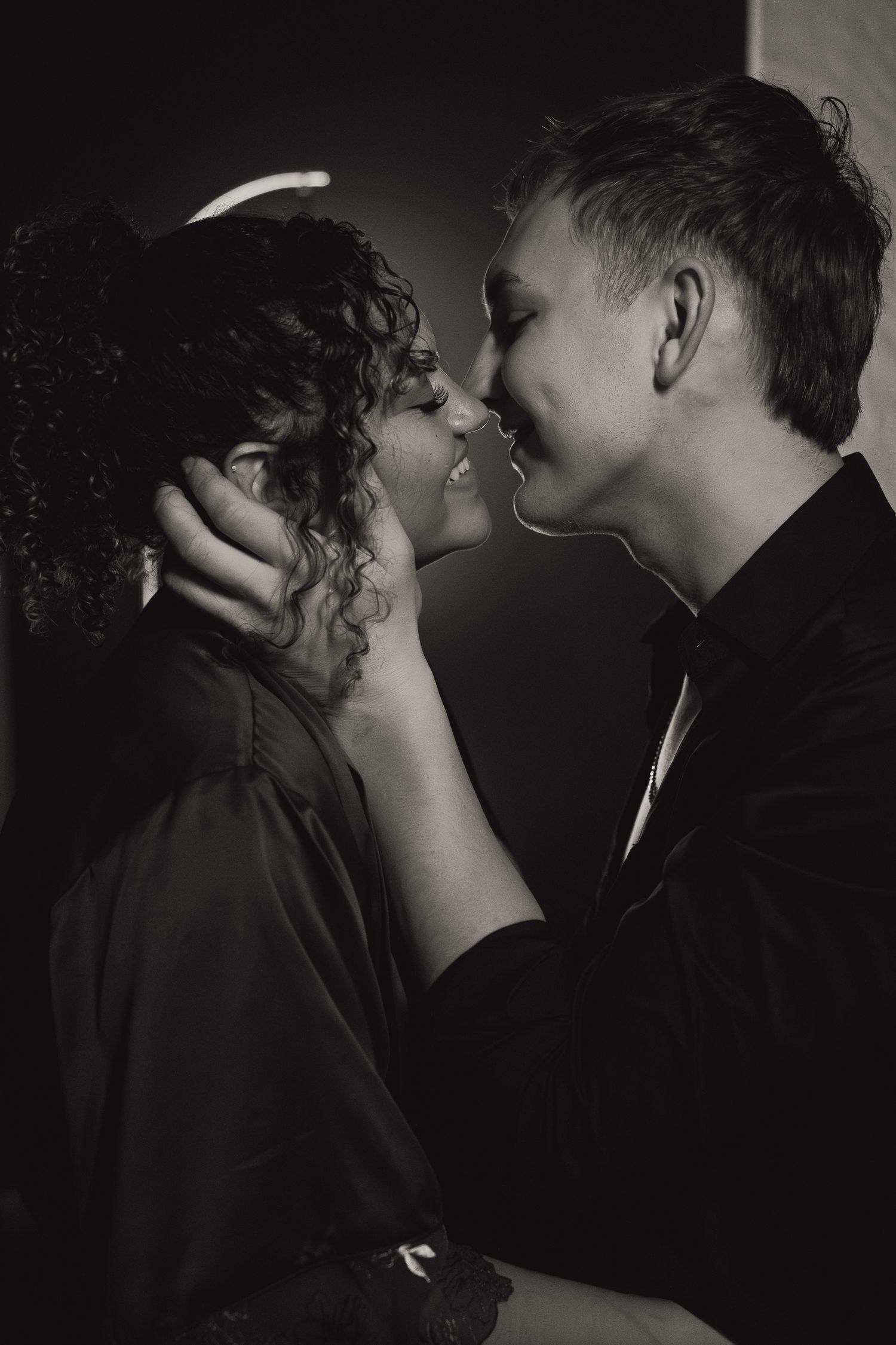 Black and white romantic photo of a couple sharing an intimate kiss in dramatic moody lighting in the pearl district of Portland, Oregon.