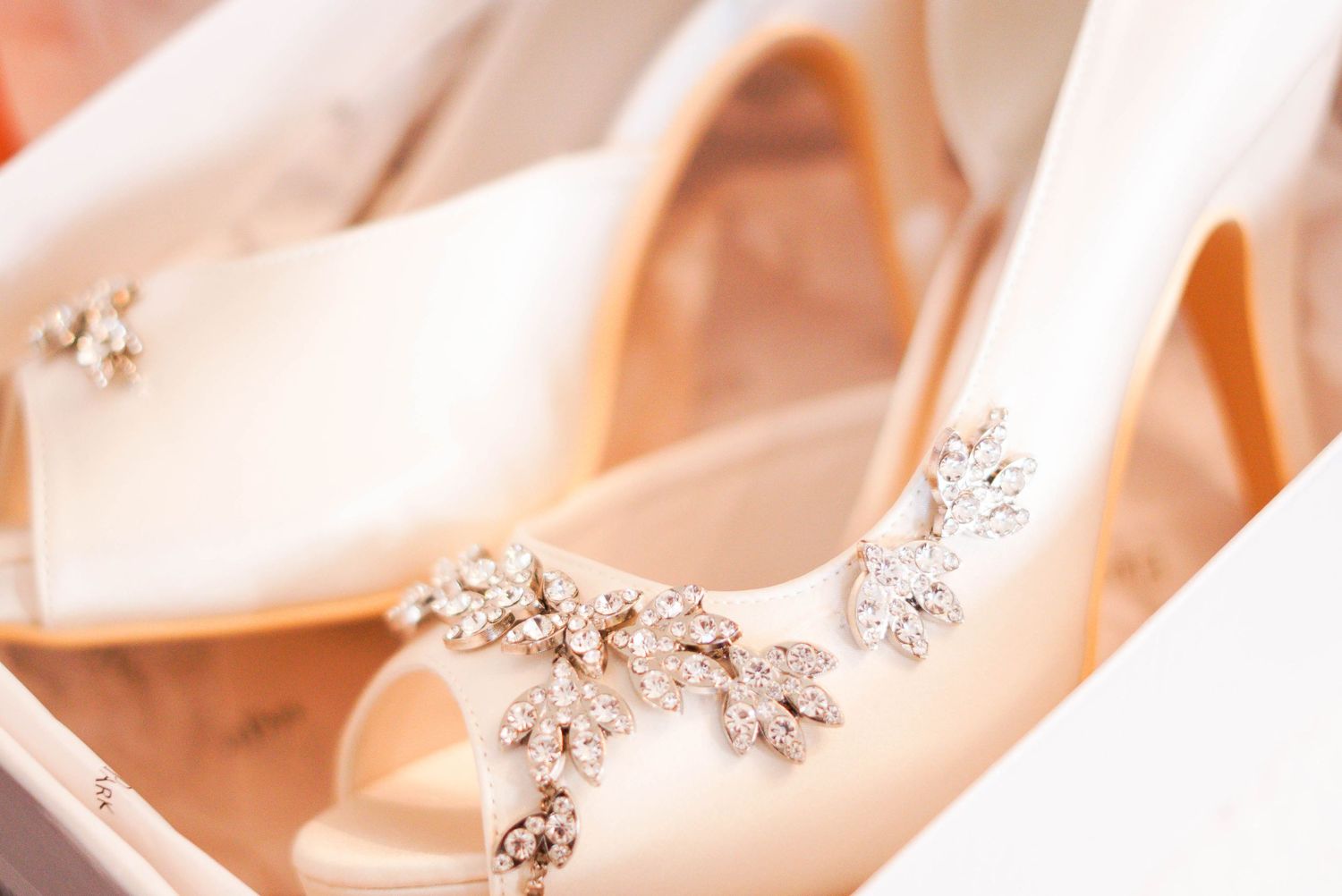 Close-up of elegant ivory bridal heels adorned with sparkling crystal floral embellishments.