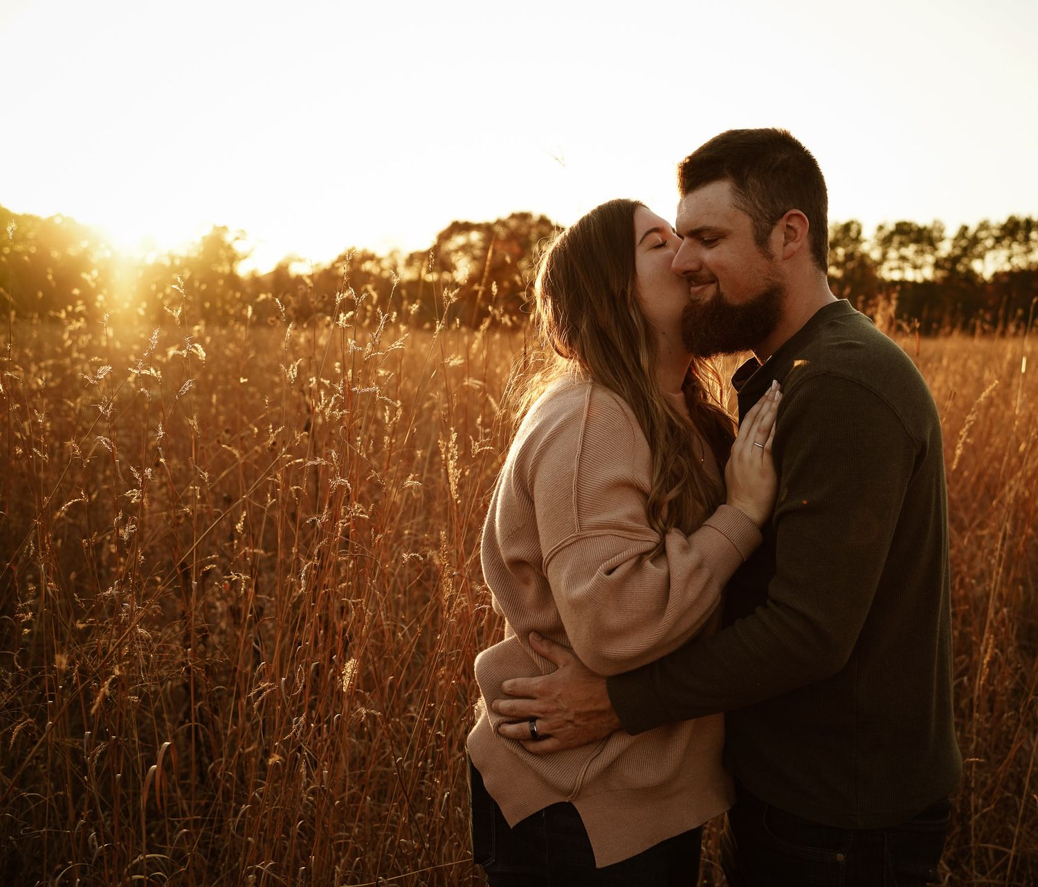 Wisconsin Couple and Engagement Photographer - Couple kissing in fall during sunset during engagement session in a field.