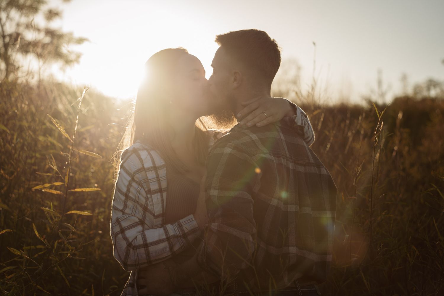 Wisconsin Couple and Engagement Photographer - Couple kissing in a field in fall during an engagement session in WI during sunset.