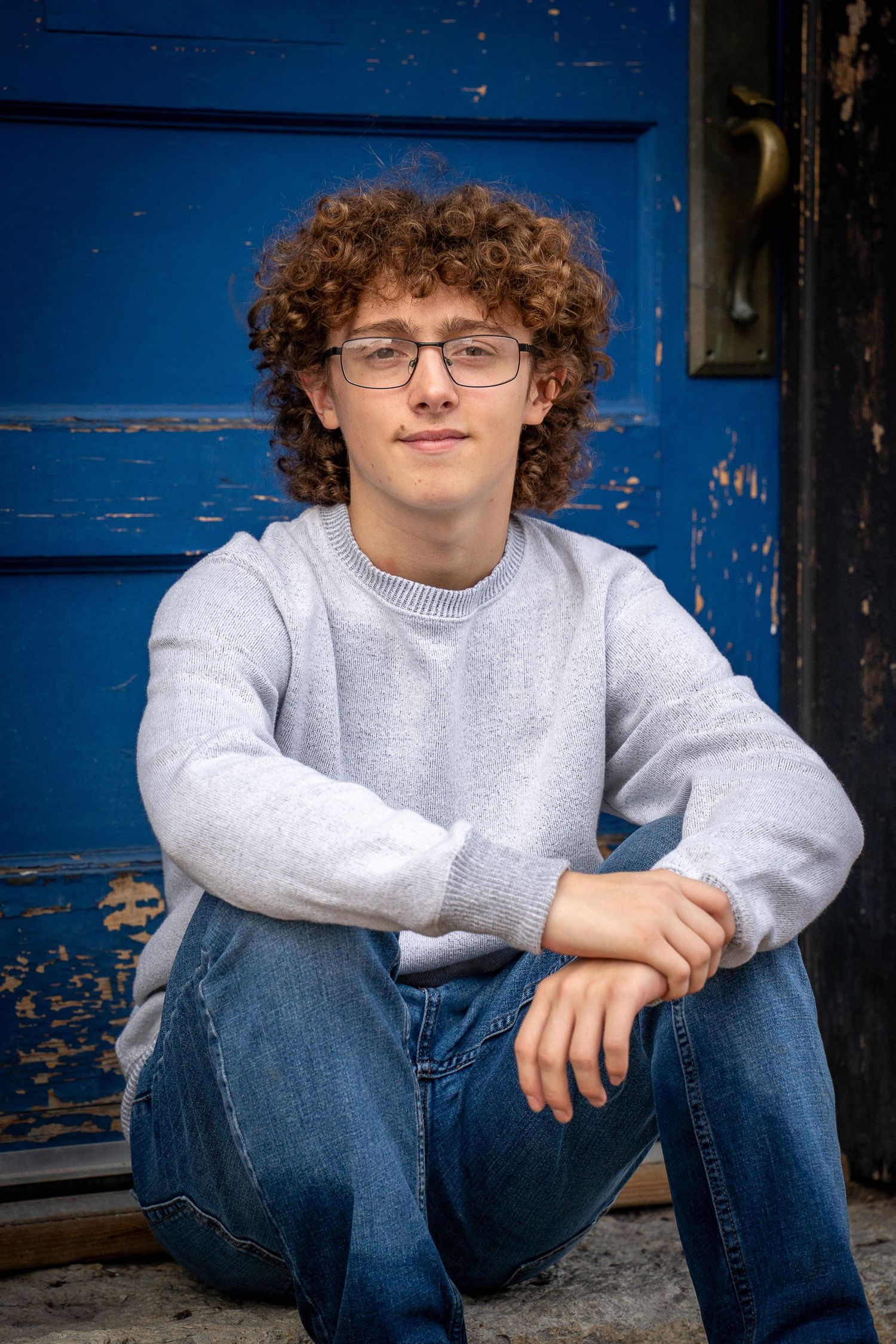 Wisconsin Senior and Portrait Photographer - Boy sitting in front of blue door during a senior session in Wisconsin in the summer.