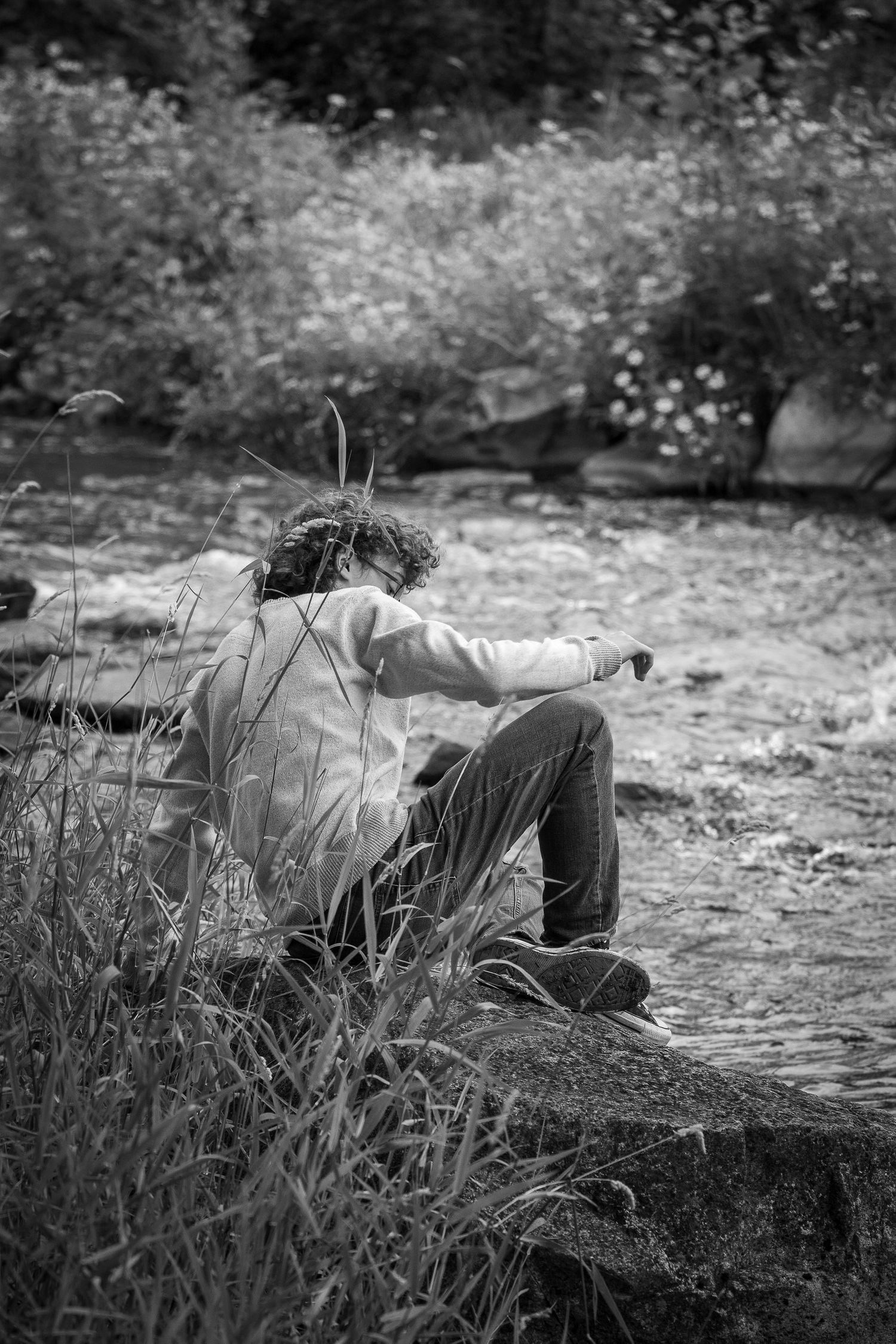 Wisconsin Senior and Portrait Photographer - Boy sitting on a rock on river smiling in Wisconsin during a summer senior portrait session.