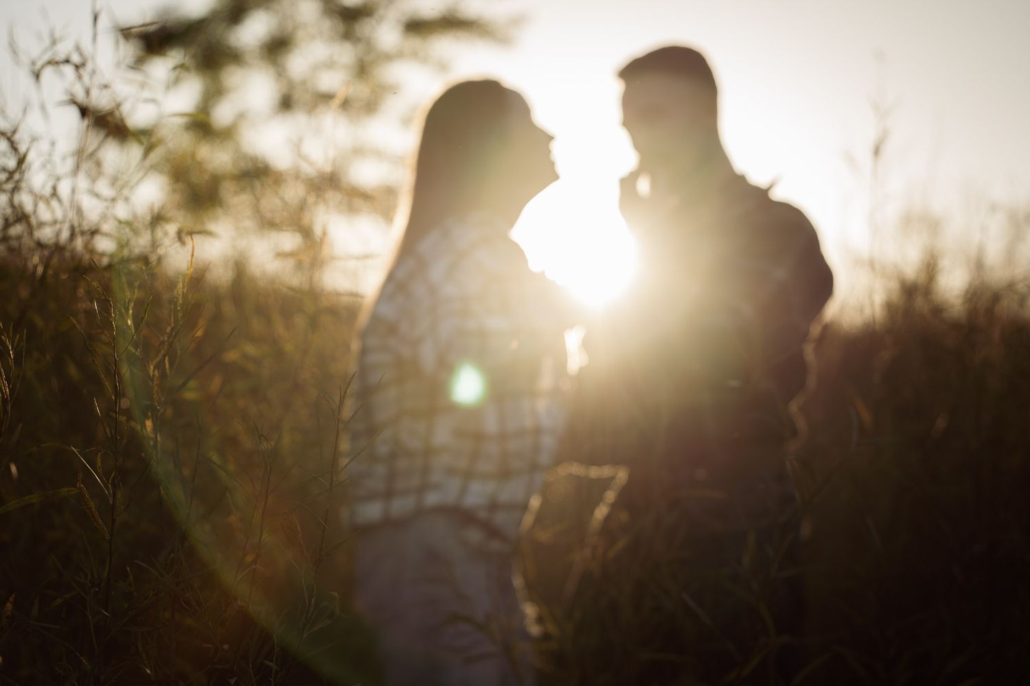 Wisconsin Couple and Engagement Photographer - Couple laughing in a field in fall during an engagement session in WI during sunset.