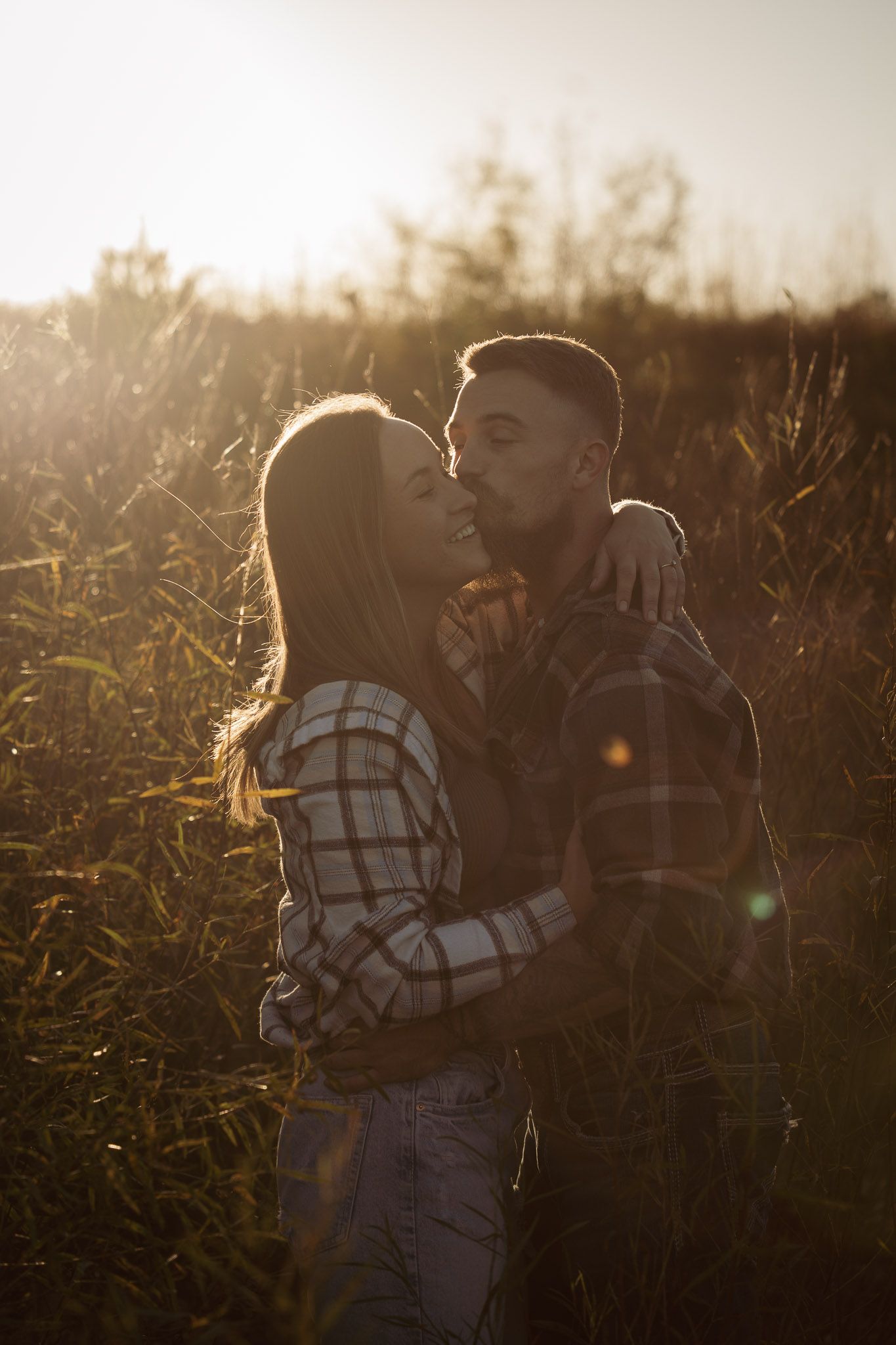 Wisconsin Couple and Engagement Photographer - Couple kissing in a field in fall during an engagement session in WI during sunset.