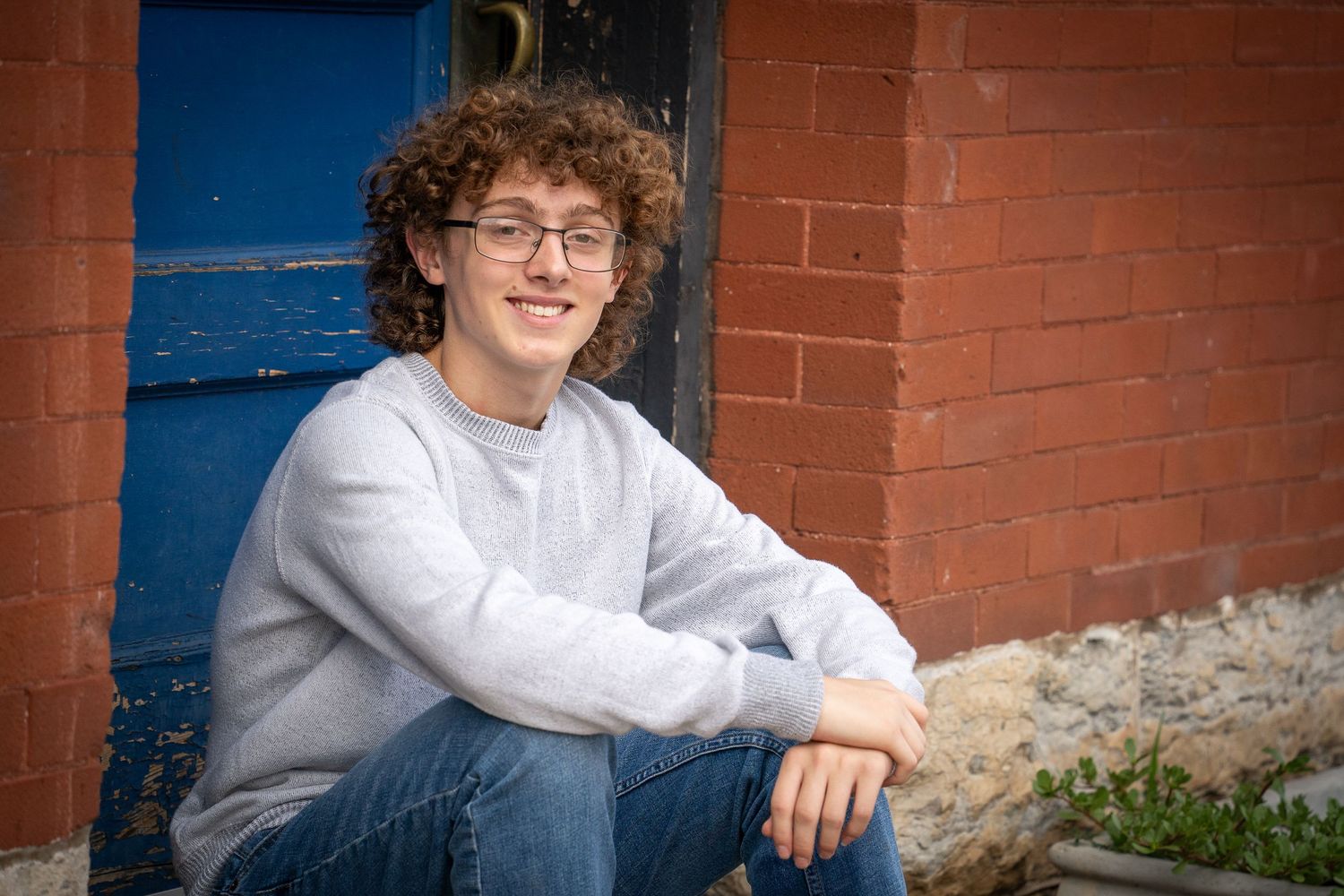 Wisconsin Senior and Portrait Photographer - Boy sitting in front of blue door during a senior session in Wisconsin in the summer.