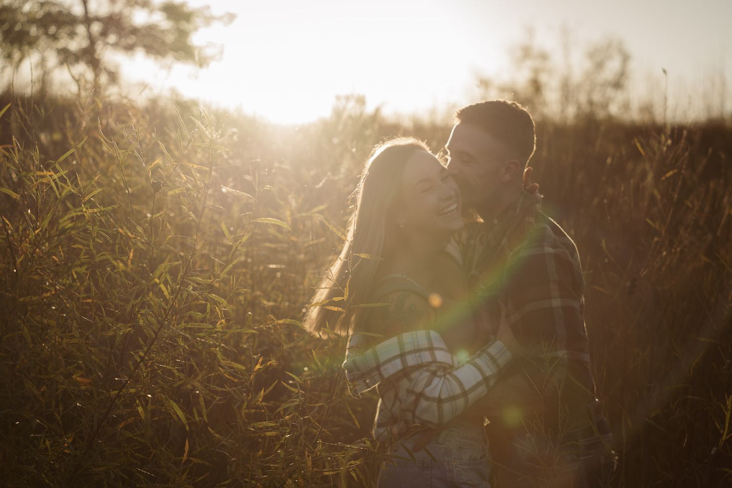 Wisconsin Couple and Engagement Photographer - Couple laughing in a field in fall during an engagement session in WI during sunset.