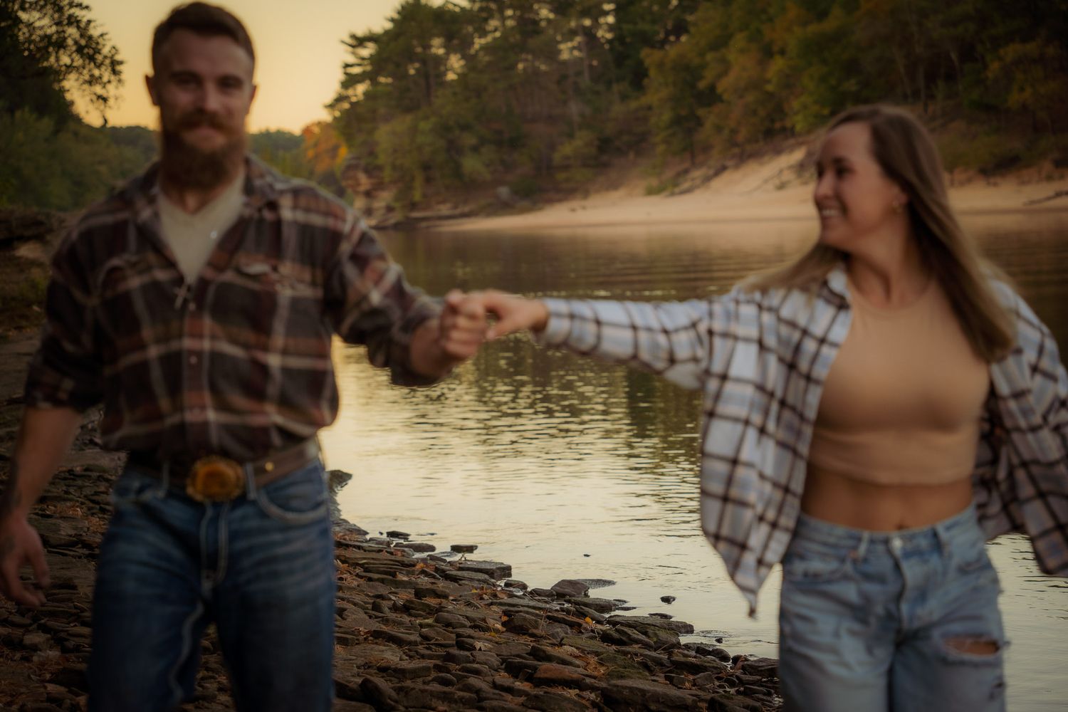 Wisconsin Couple and Engagement Photographer - Couple walking on riverbank in fall during engagement session in Wisconsin during sunset.