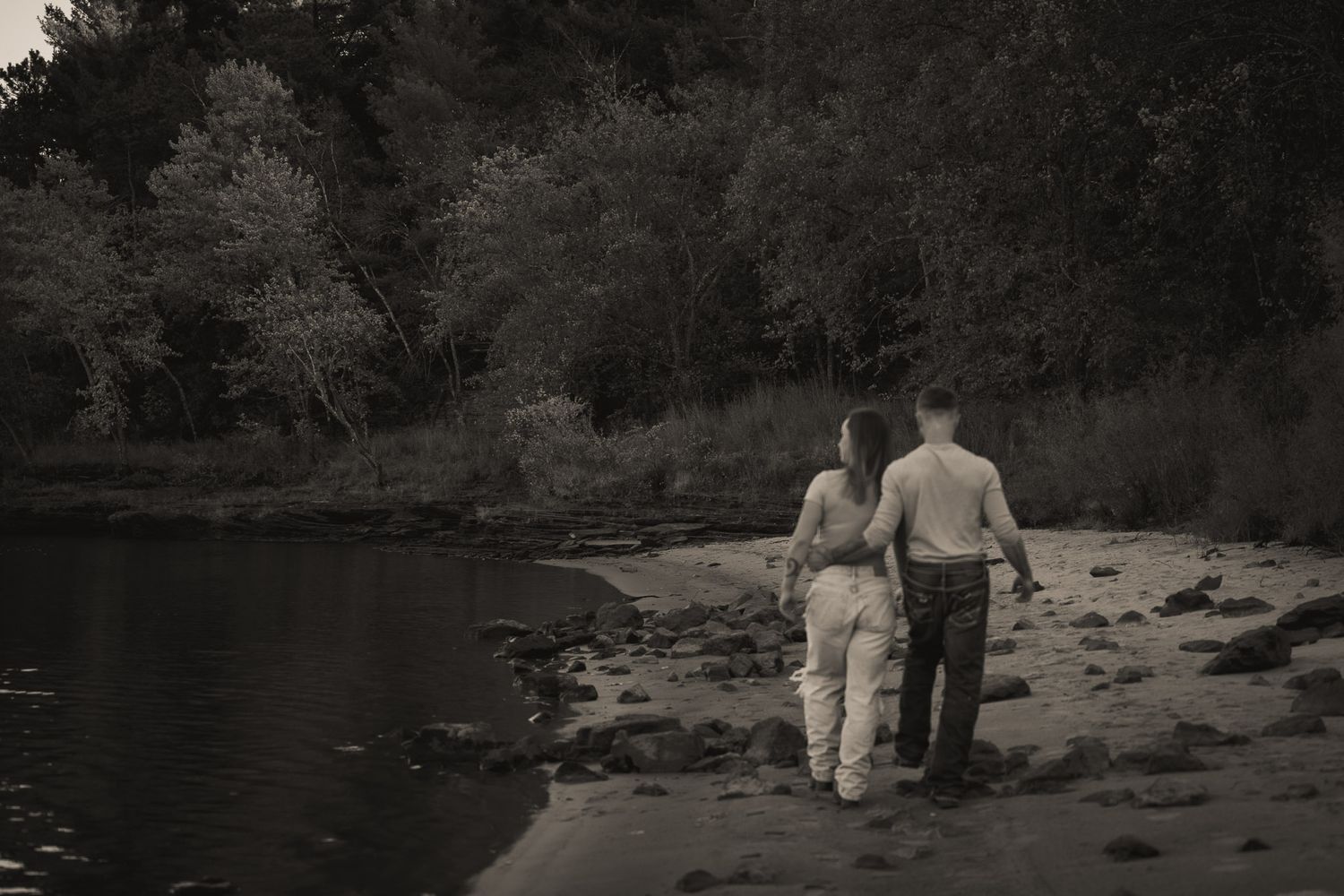 Wisconsin Couple and Engagement Photographer - Couple walking on riverbank in fall during an engagement session in Wisconsin during sunset.