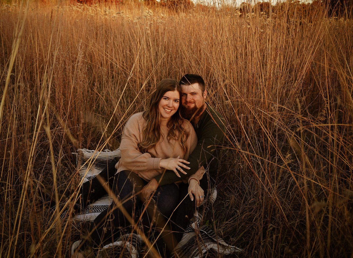 Wisconsin Couple and Engagement Photographer - Couple sitting in a field in fall during an engagement session in Wisconsin during sunset.