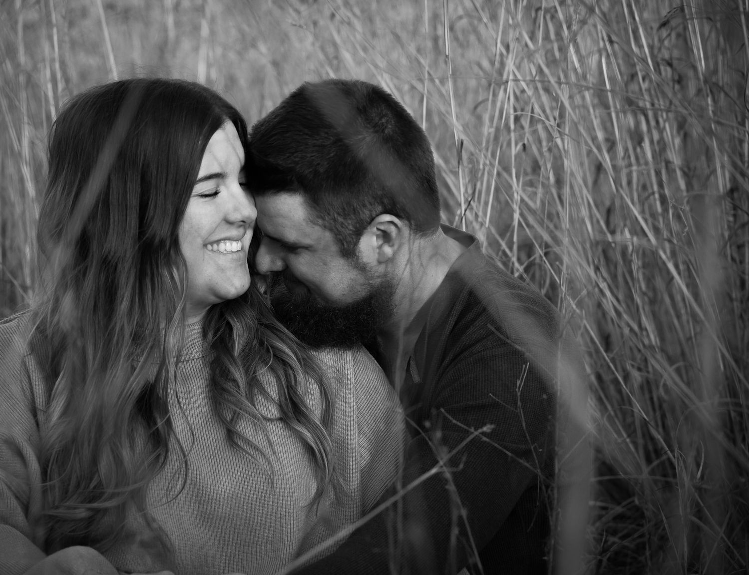 Wisconsin Couple and Engagement Photographer - Couple sitting in a field in fall during an engagement session during sunset in Wisconsin.