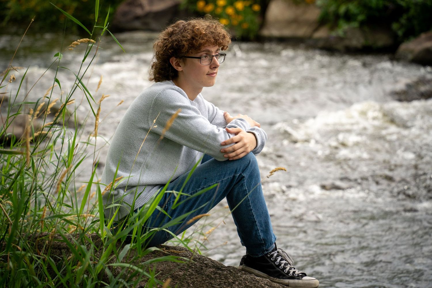 Wisconsin Senior and Portrait Photographer - Boy sitting on a rock on river smiling in Wisconsin during a summer senior portrait session.