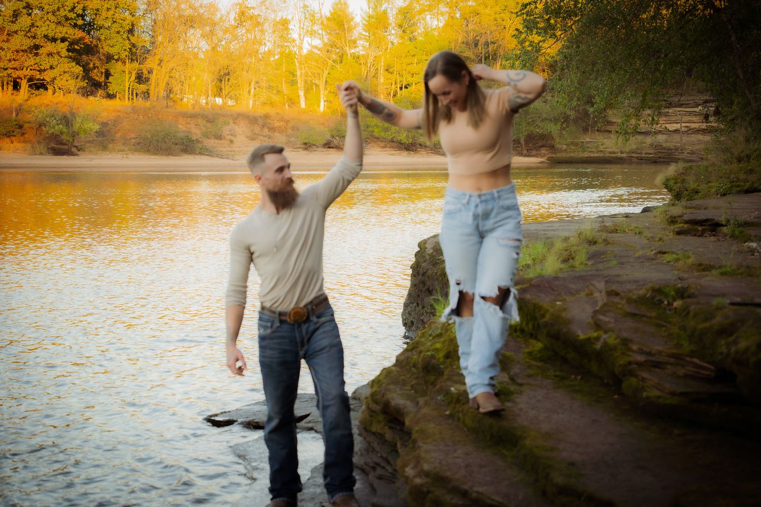 Wisconsin Couple and Engagement Photographer - Couple walking on riverbank in fall during an engagement session in Wisconsin during sunset.