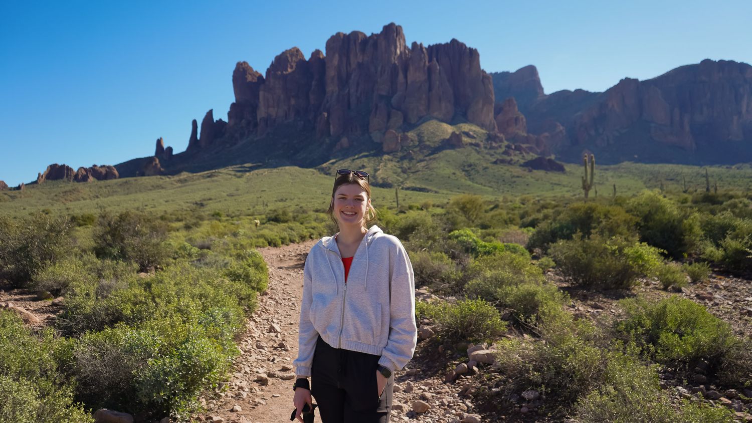 Wisconsin Portrait and Lifestyle Photographer - Beautiful woman hiking towards a mountain in Arizona in the sun smiling.