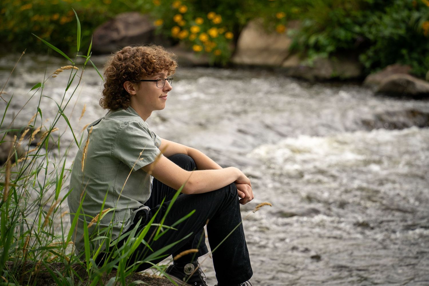 Wisconsin Senior and Portrait Photographer - Boy sitting on a rock on river smiling in Wisconsin during a summer senior portrait session.