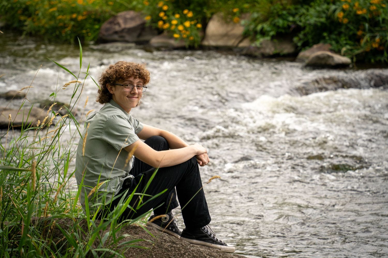 Wisconsin Senior and Portrait Photographer - Boy sitting on a rock on river smiling in Wisconsin during a summer senior portrait session.