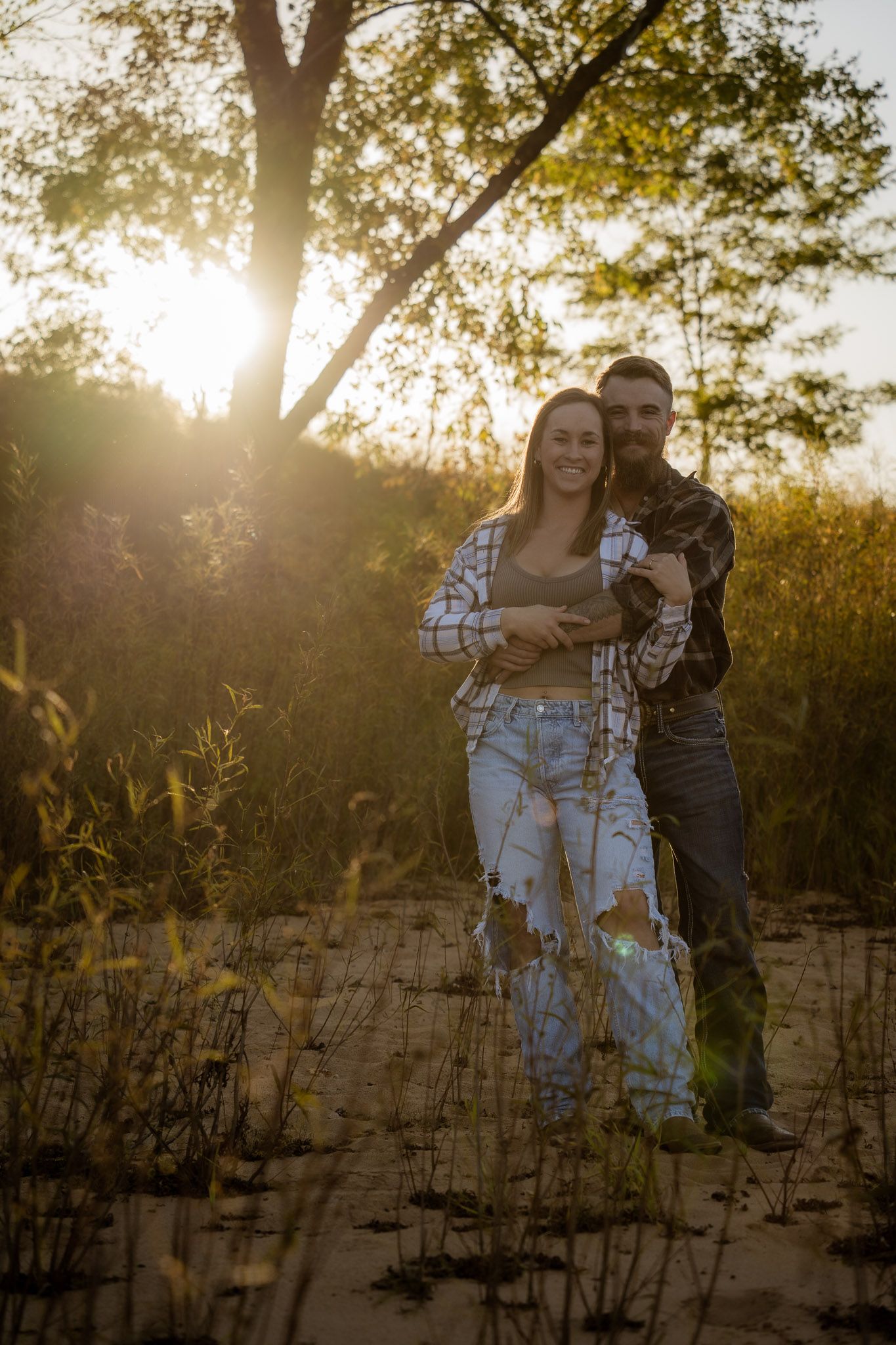 Wisconsin Couple and Engagement Photographer - Couple posing on a beach in fall during an engagement session in Wisconsin during sunset.