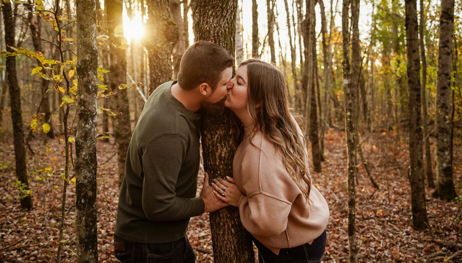 Wisconsin Couple and Engagement Photographer - Couple kissing in woods in fall during an engagement session during sunset in Wisconsin.