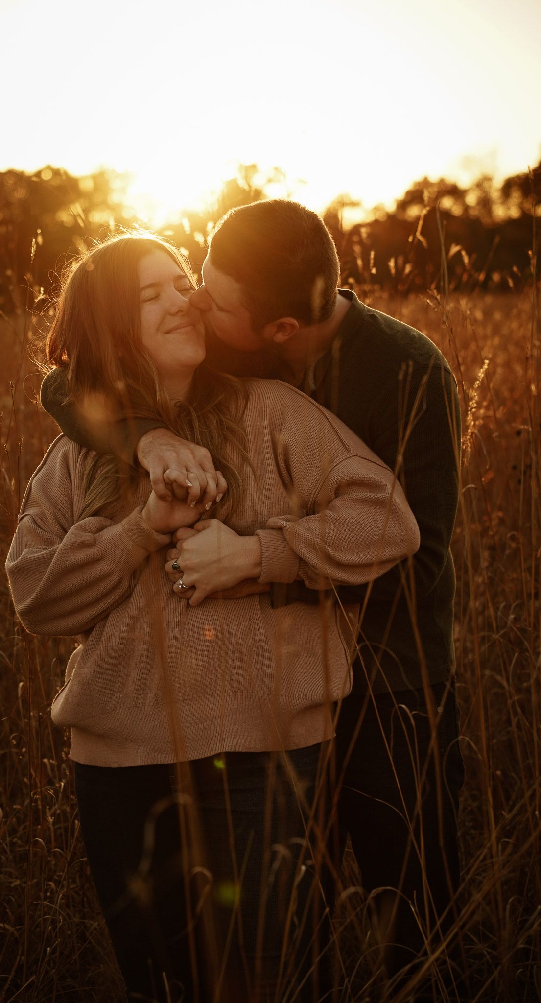 Wisconsin Couple and Engagement Photographer - Couple hugging in a field in fall during an engagement session during sunset.