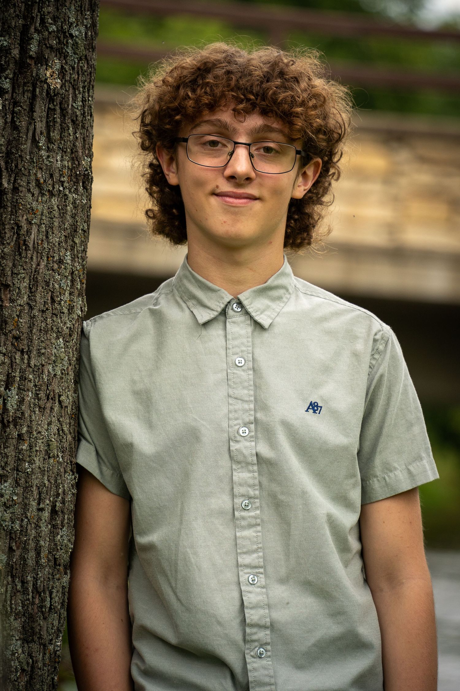 Wisconsin Senior and Portrait Photographer - Boy leaning on a tree next to a bridge in Wisconsin during a summer senior portrait session.