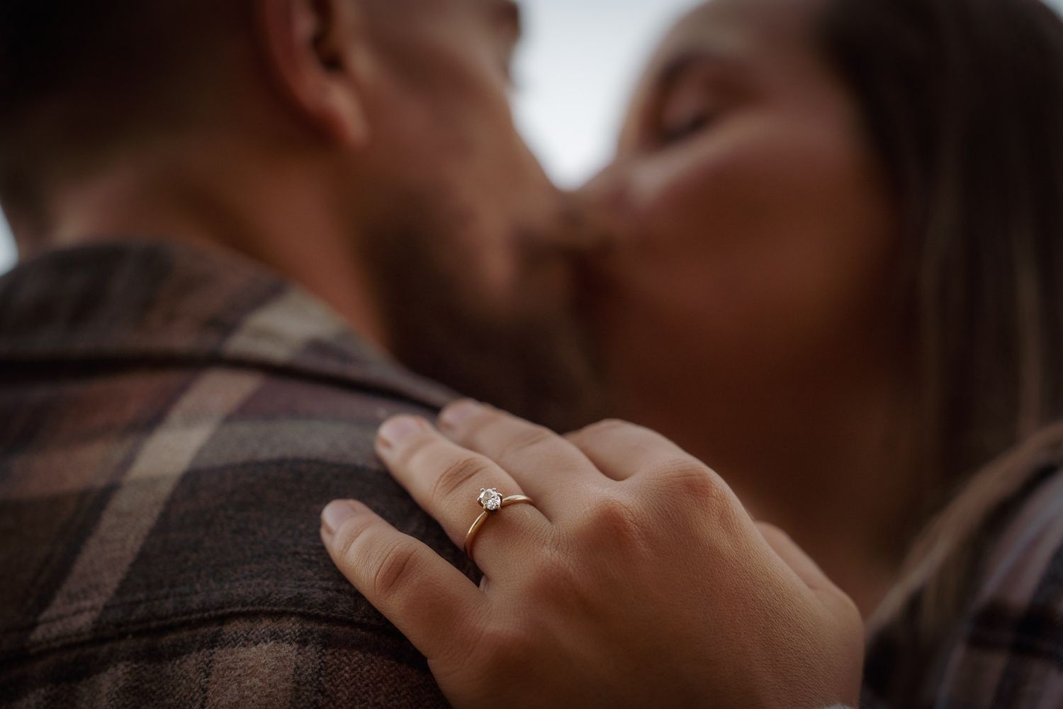 Wisconsin Couple and Engagement Photographer - Beautiful photo of engagement ring on hand with couple kissing during fall engagement photos.