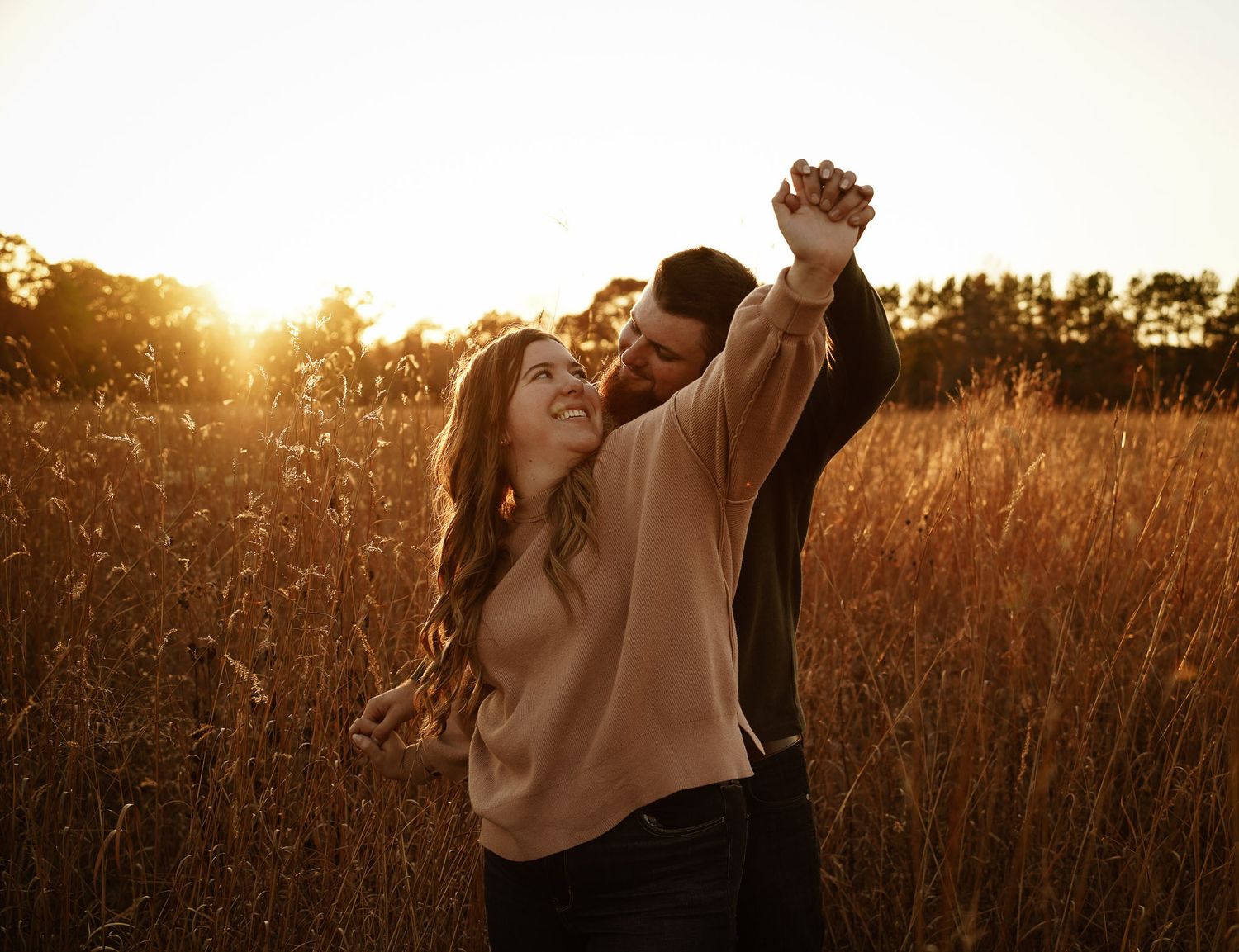 Wisconsin Couple and Engagement Photographer - Couple holding hands in a field in fall during an engagement session during sunset.