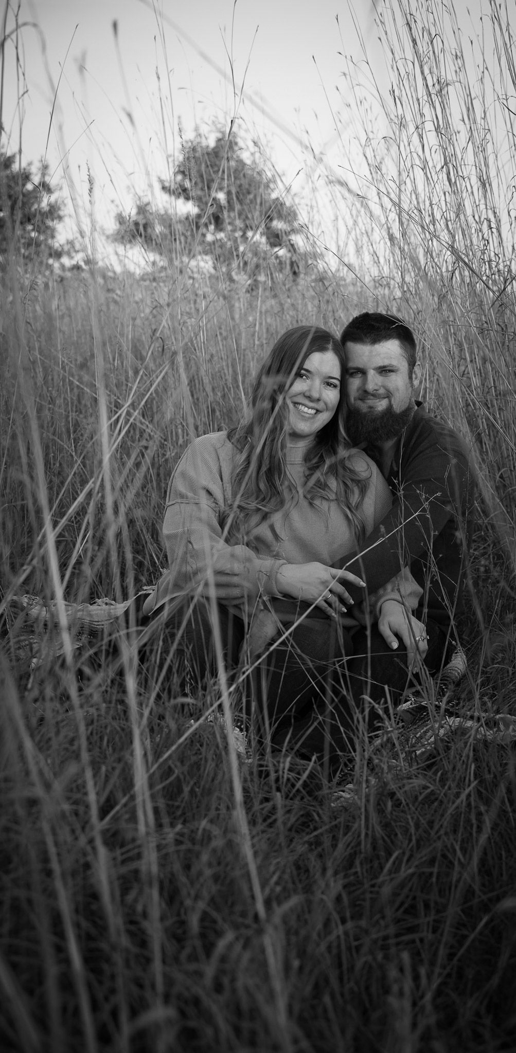 Wisconsin Couple and Engagement Photographer - Couple sitting in a field in fall during an engagement session during sunset, black and white