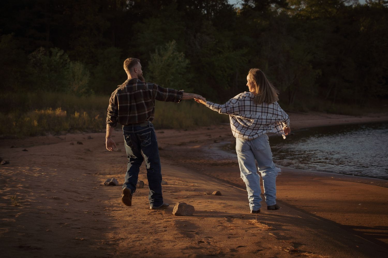 Wisconsin Couple and Engagement Photographer - Couple running on a beach in fall during an engagement session in Wisconsin during sunset.