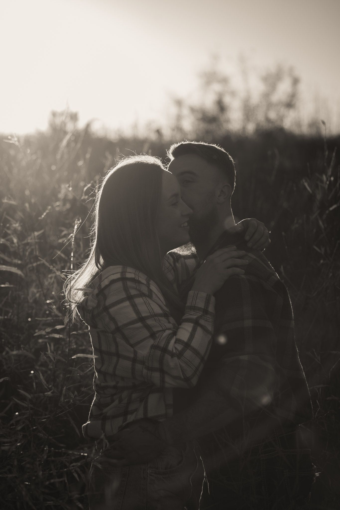 Wisconsin Couple and Engagement Photographer - Couple kissing in a field in fall during an engagement session in WI during sunset.