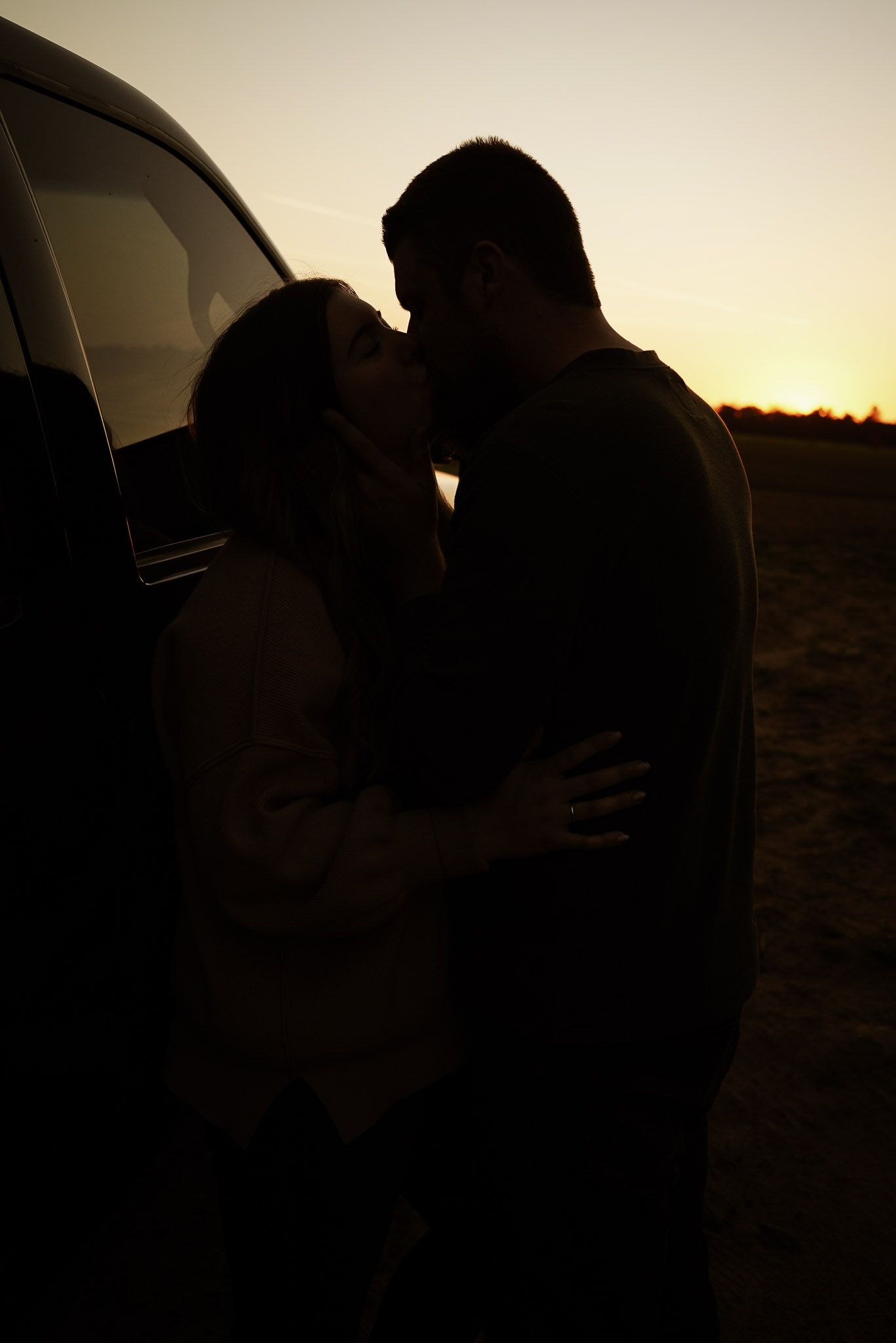 Wisconsin Couple and Engagement Photographer - Sunset photo of couple silhouette during engagement session with a trucks in a field.