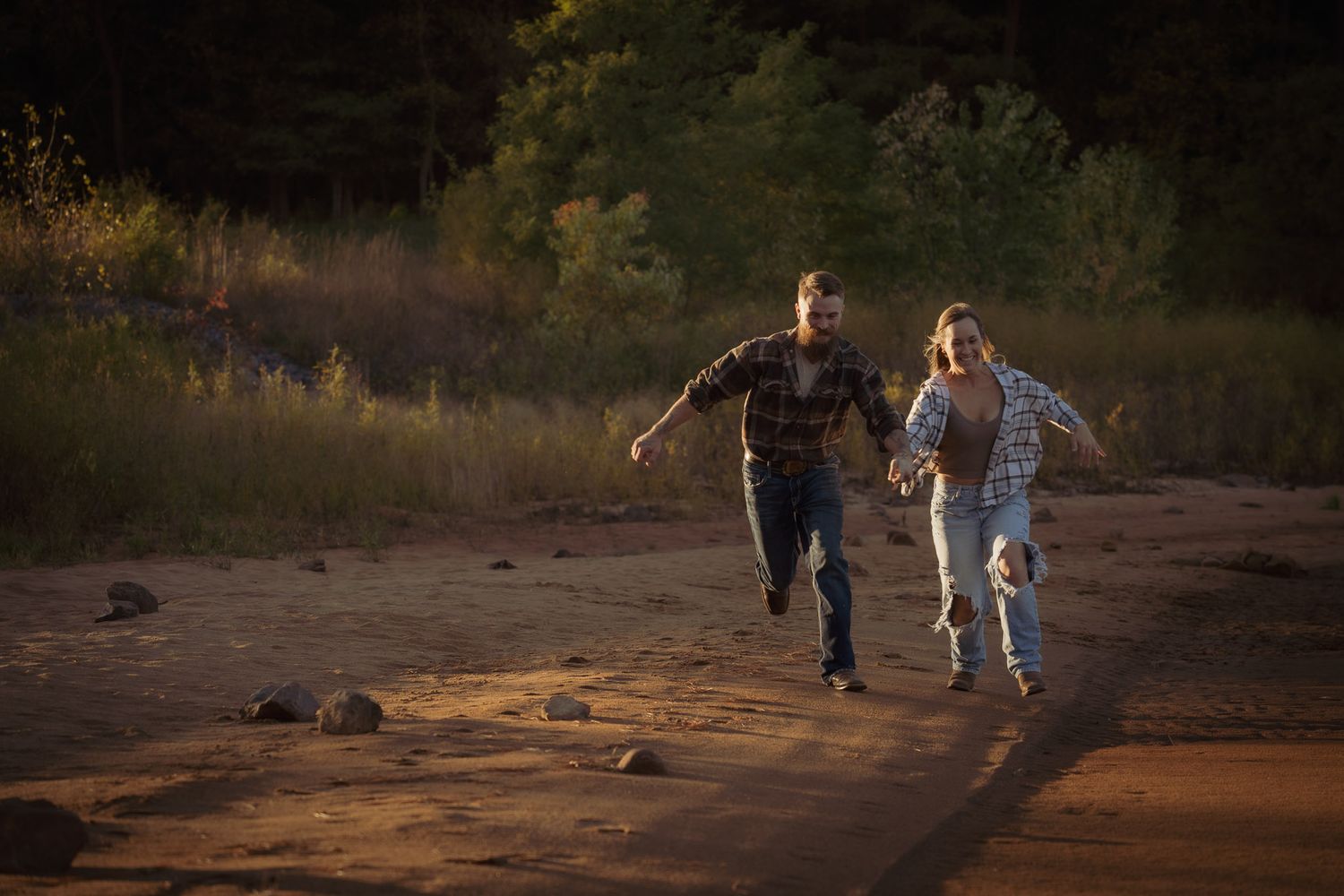 Wisconsin Couple and Engagement Photographer - Couple running on a beach in fall during an engagement session in Wisconsin during sunset.