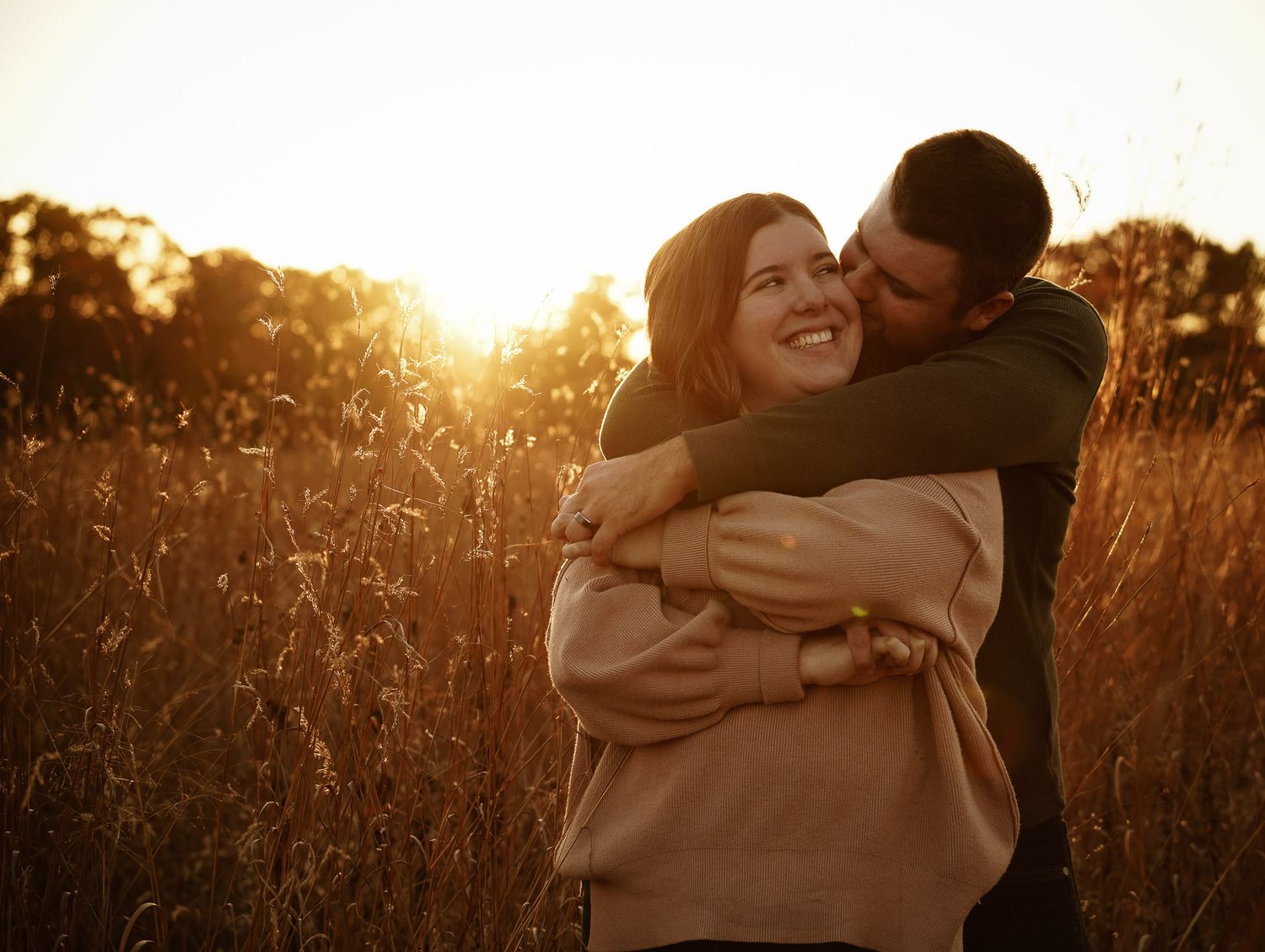 Wisconsin Couple and Engagement Photographer - Couple hugging in a field in fall during an engagement session during sunset.