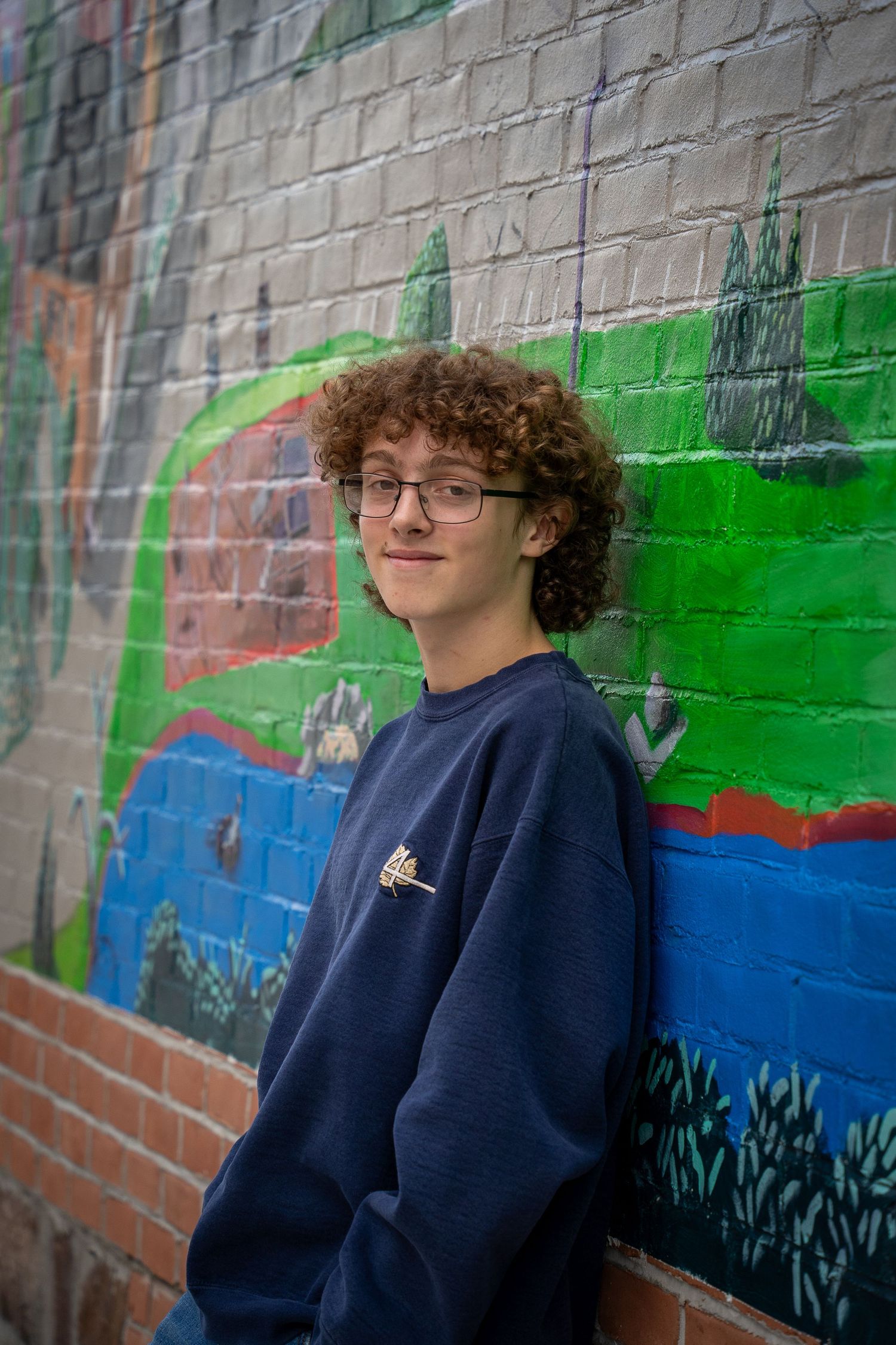 Wisconsin Senior and Portrait Photographer - Boy leaning on wall with city street art in Wisconsin during a summer senior portrait session.