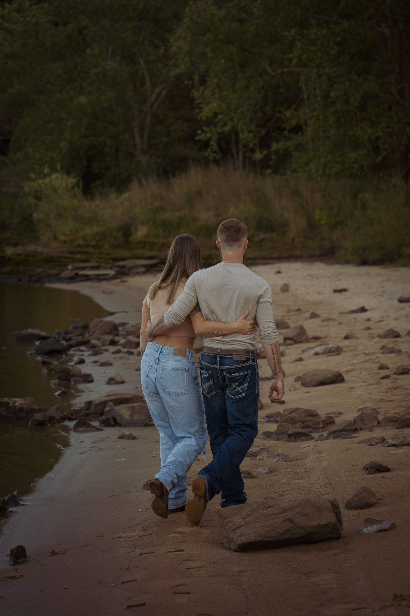 Wisconsin Couple and Engagement Photographer - Couple walking on a beach in fall during an engagement session in Wisconsin during sunset.