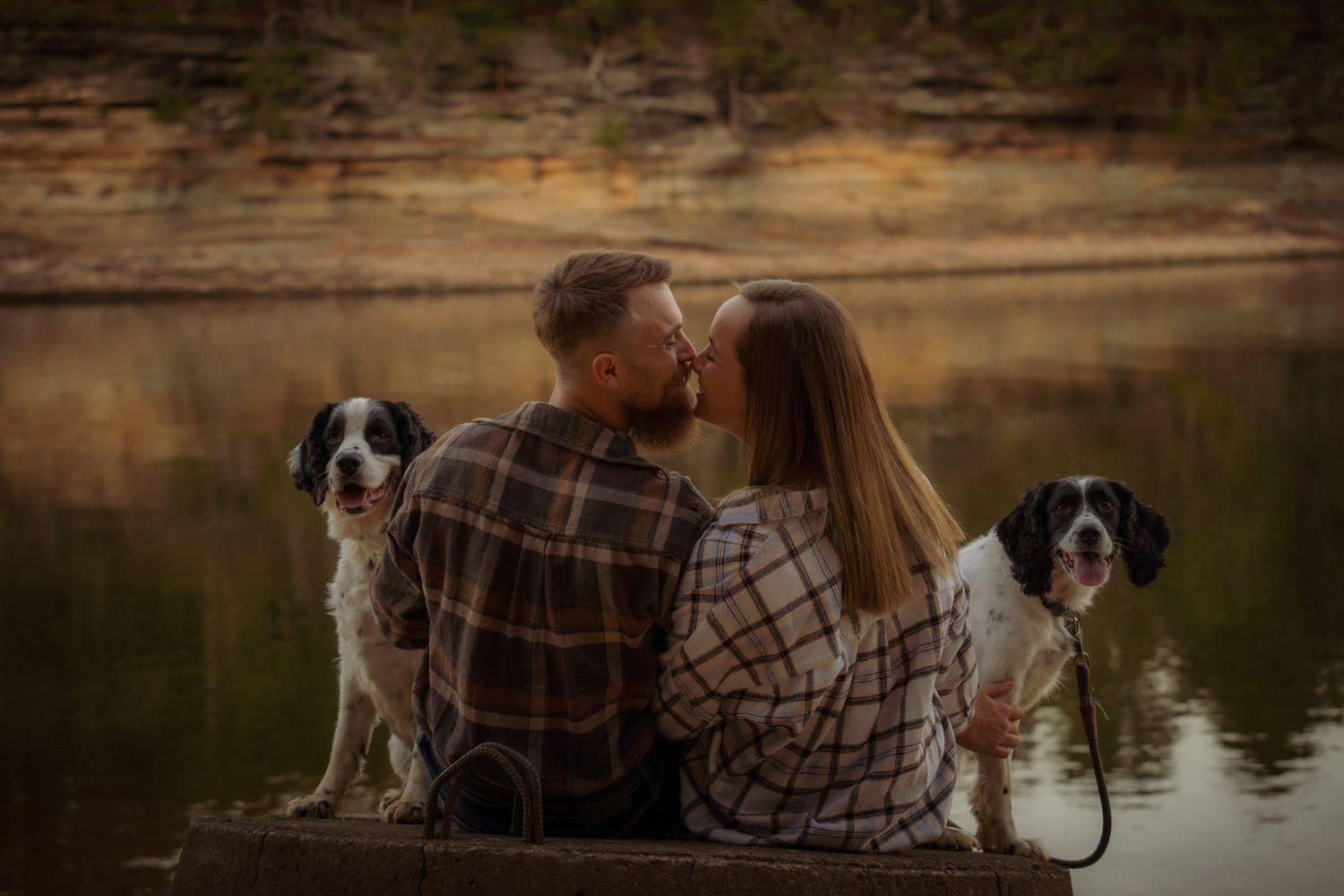 Wisconsin Couple and Engagement Photographer - Couple in plaid with two dogs on riverbank during engagement session in fall in Wisconsin.