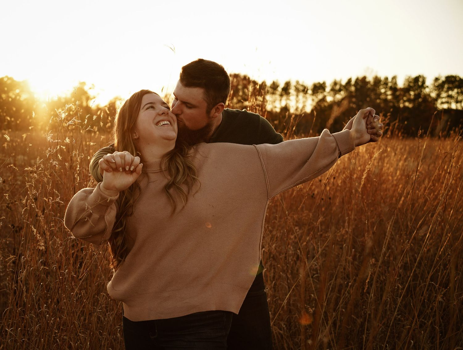 Wisconsin Couple and Engagement Photographer - Couple holding hands in a field in fall during an engagement session during sunset.