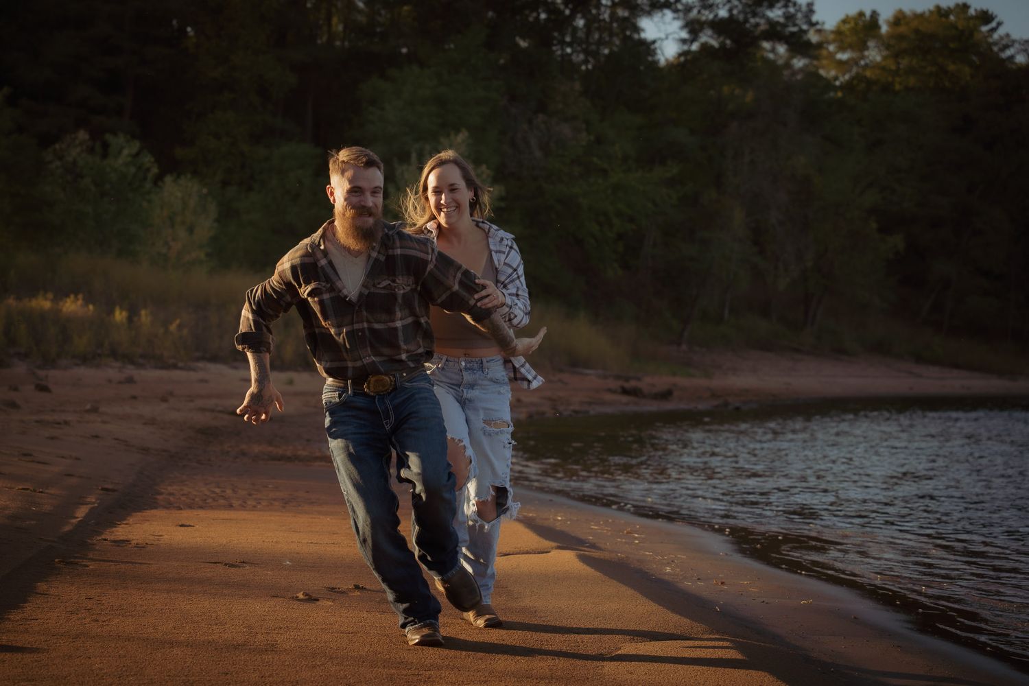 Wisconsin Couple and Engagement Photographer - Couple running on a beach in fall during an engagement session in Wisconsin during sunset.