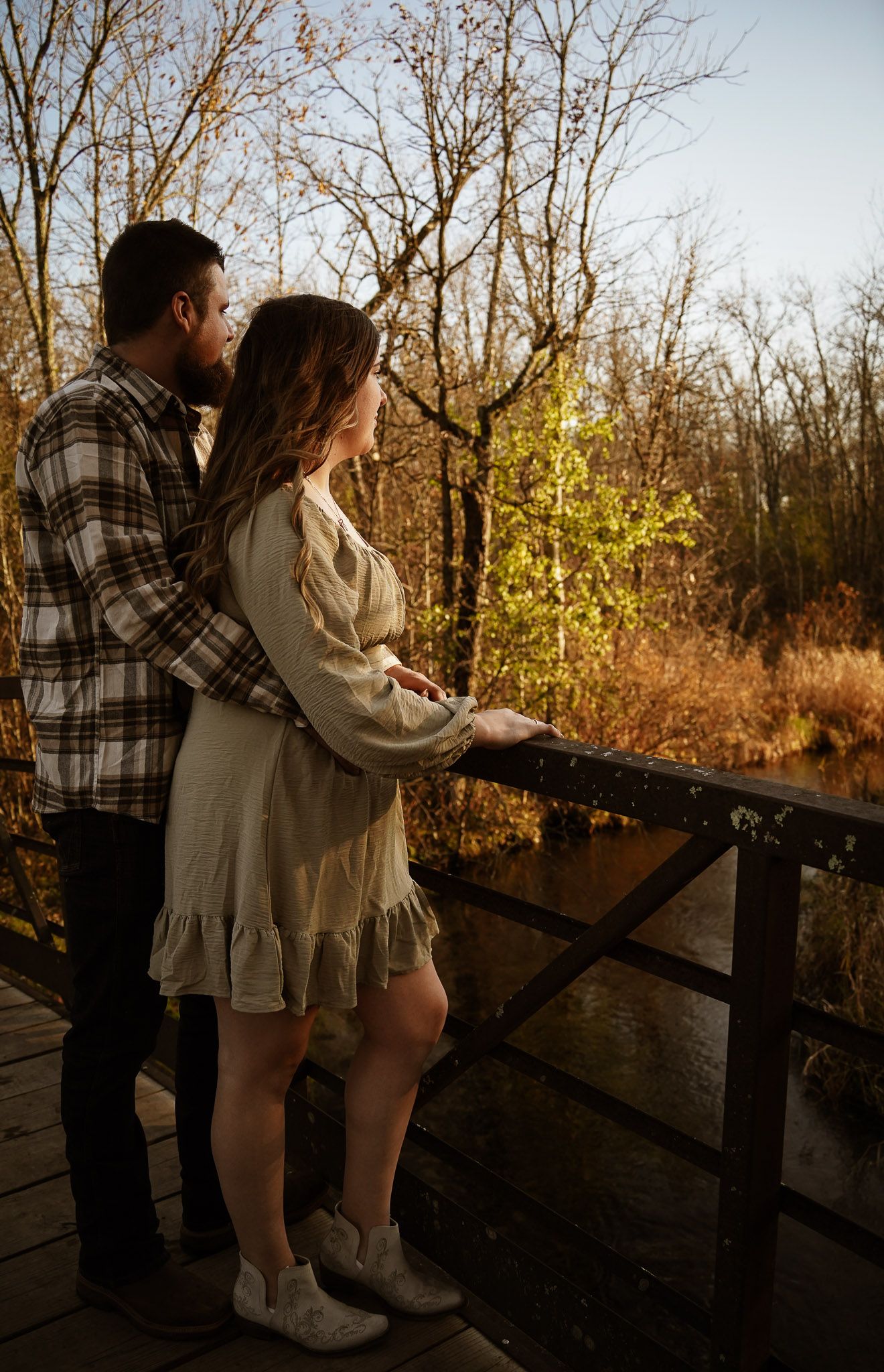 Wisconsin Couple and Engagement Photographer - Couple posing on bridge in woods in fall during an engagement session during sunset.