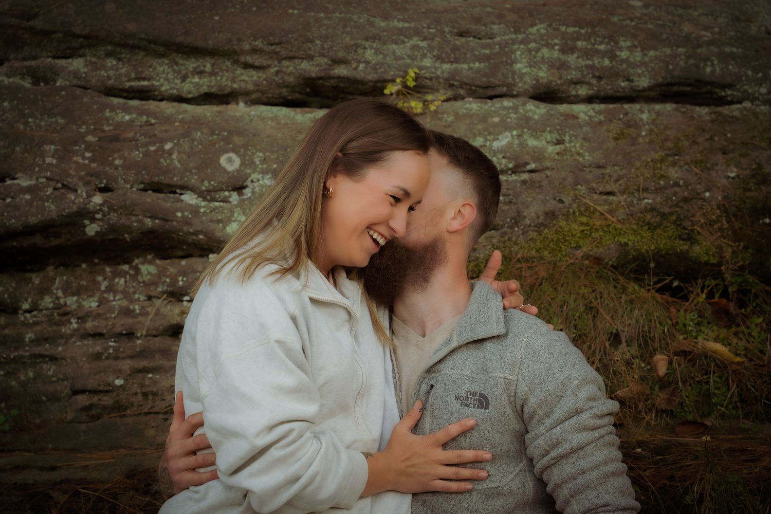 Wisconsin Couple and Engagement Photographer - Couple smiling in fall during an engagement session in Wisconsin during sunset by cliff/rocks