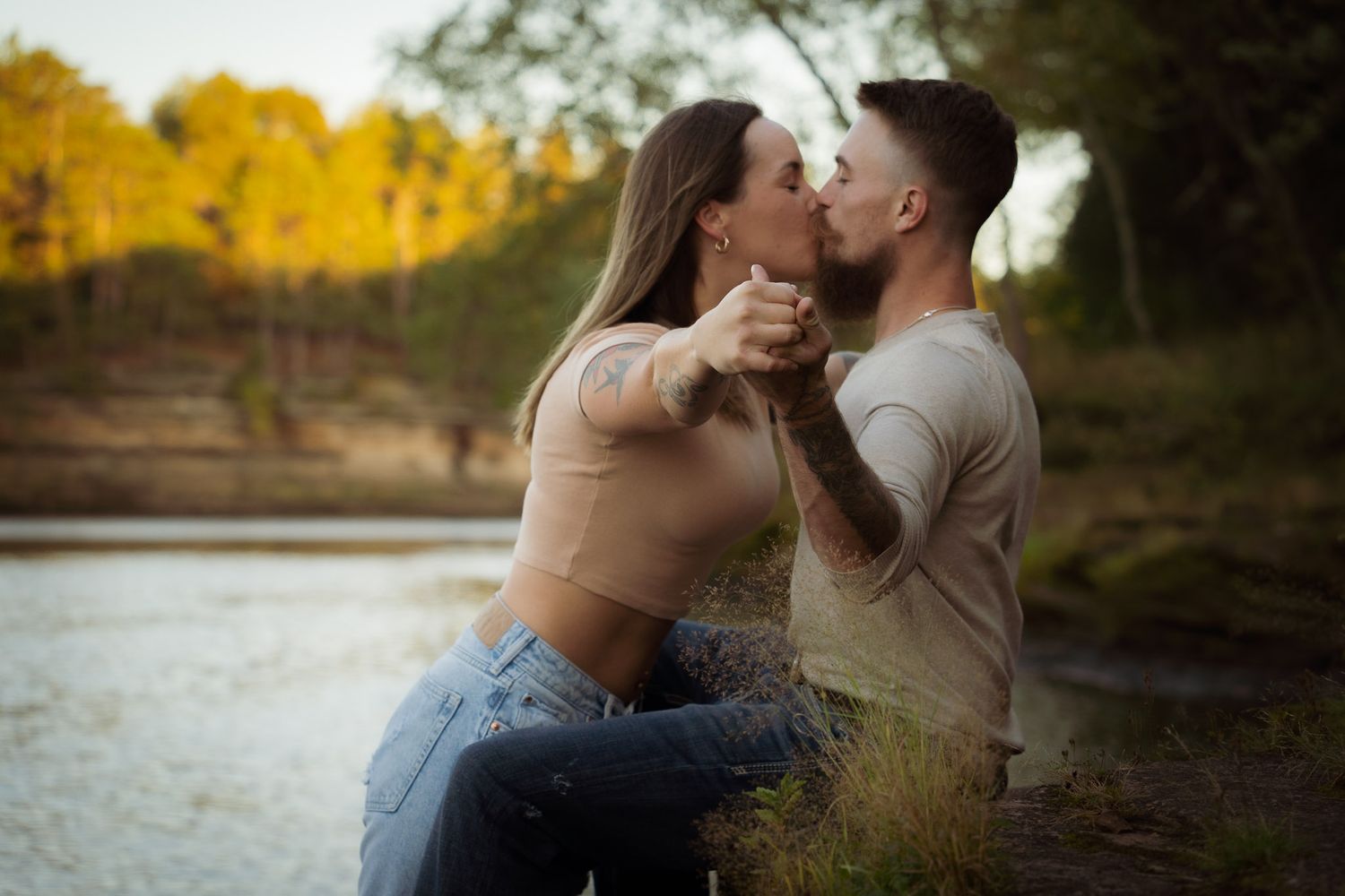 Wisconsin Couple and Engagement Photographer - Couple kissing on riverbank in fall during an engagement session in Wisconsin during sunset.