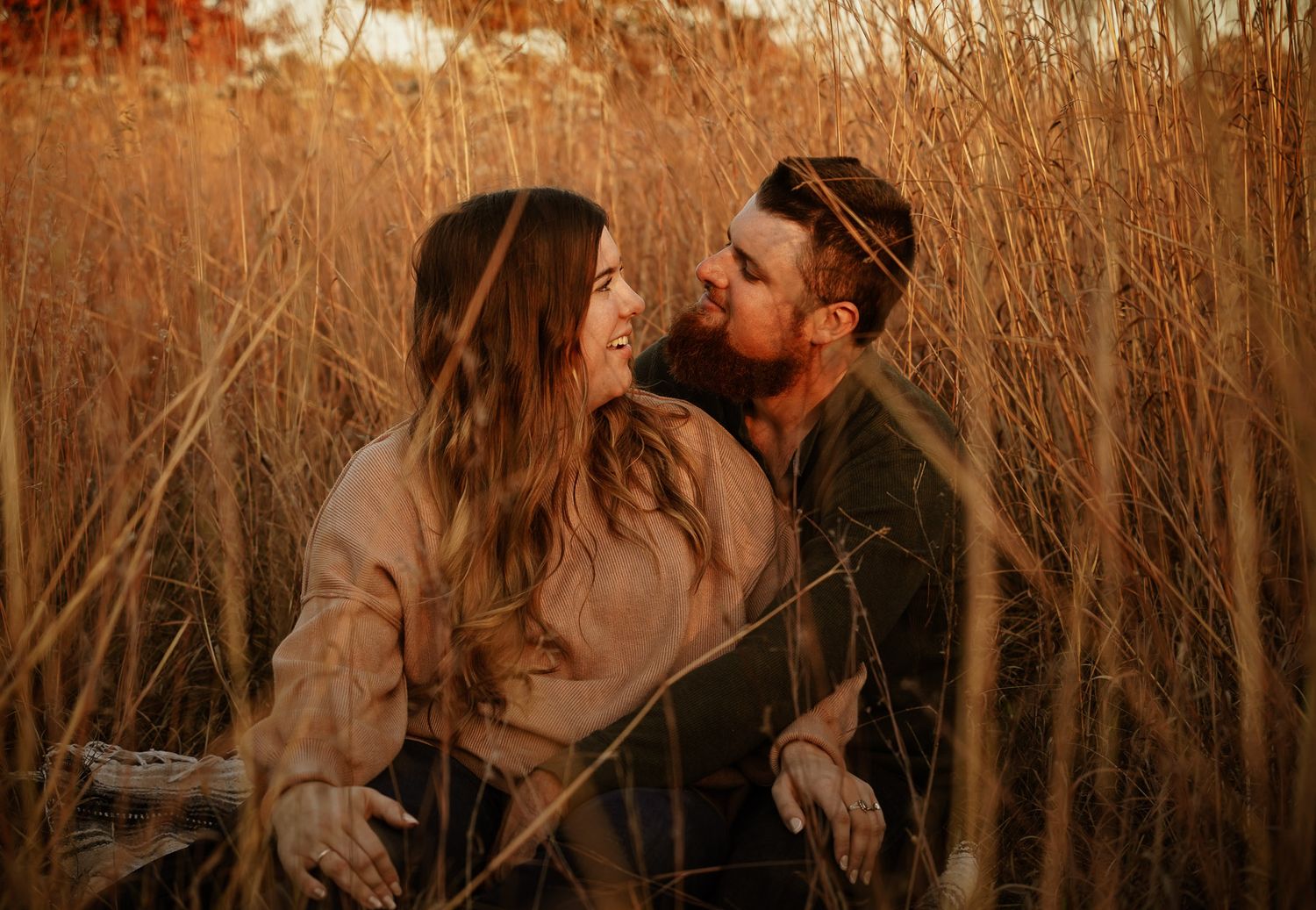 Wisconsin Couple and Engagement Photographer - Couple sitting in a field in fall during an engagement session during sunset in Wisconsin.