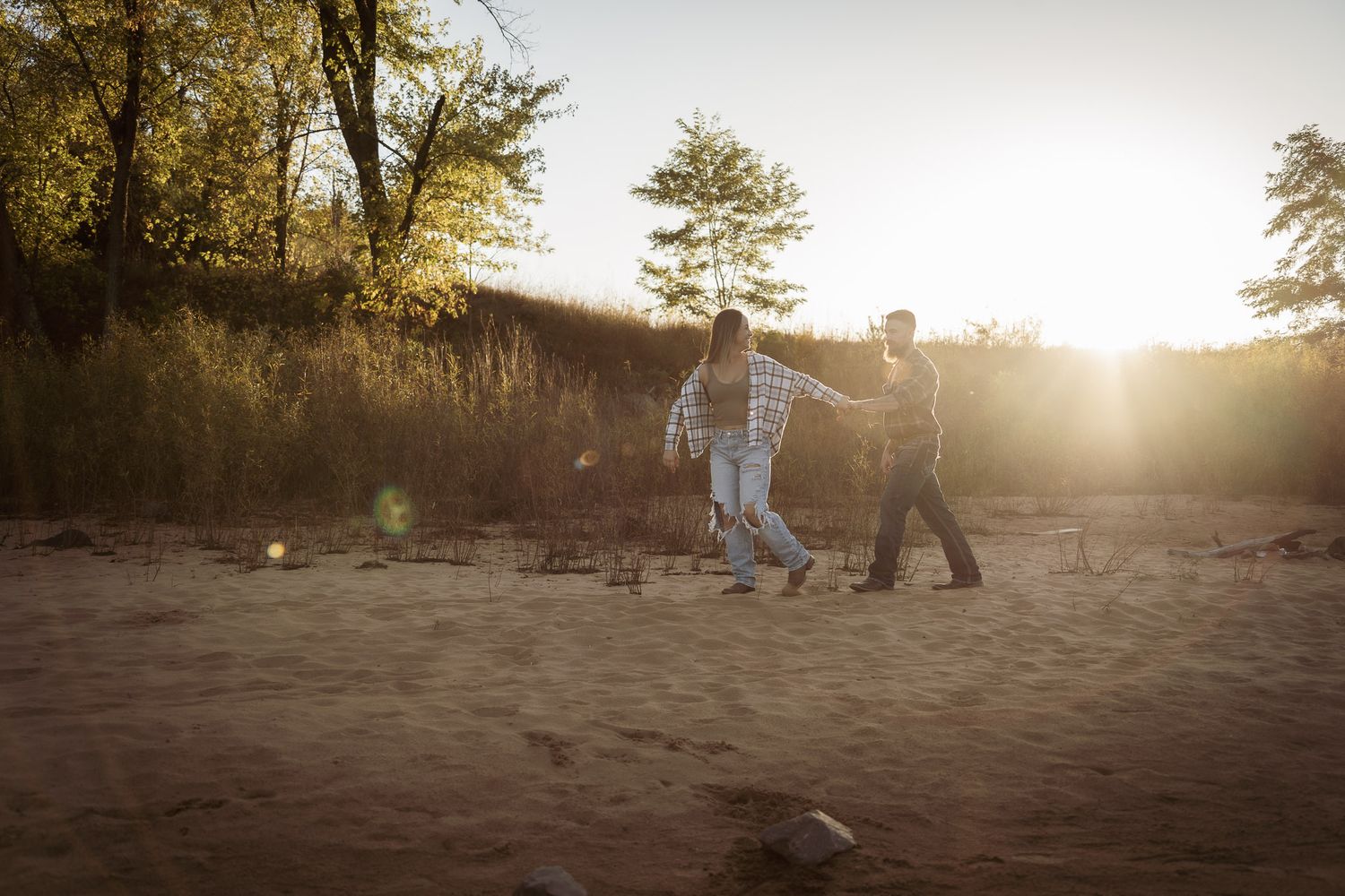Wisconsin Couple and Engagement Photographer - Couple walking on a beach in fall during an engagement session in Wisconsin during sunset.