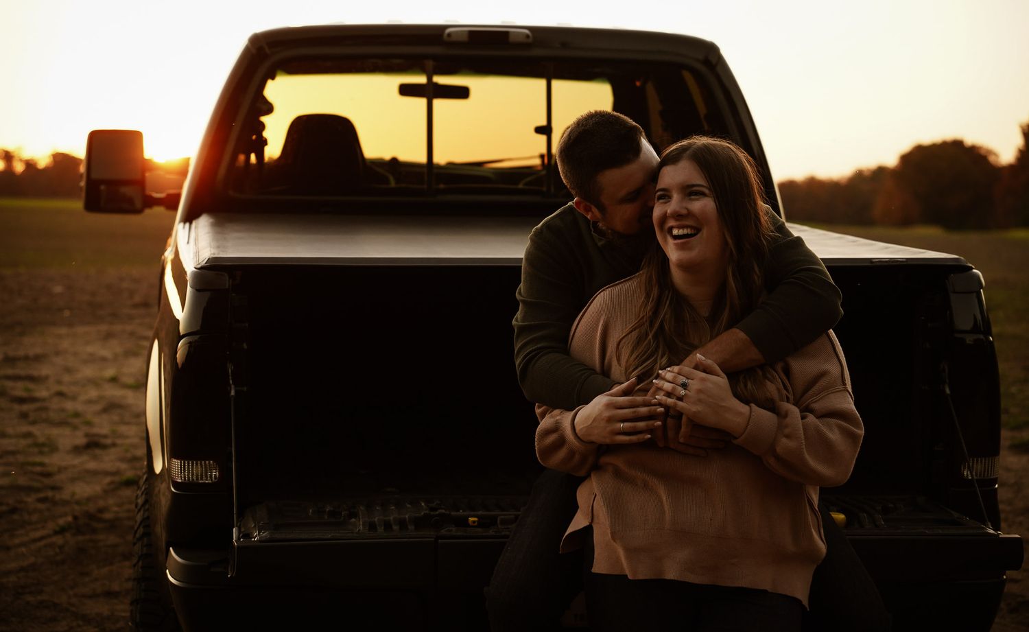 Wisconsin Couple and Engagement Photographer - Sunset photo of couple silhouette during engagement session with a trucks in a field.