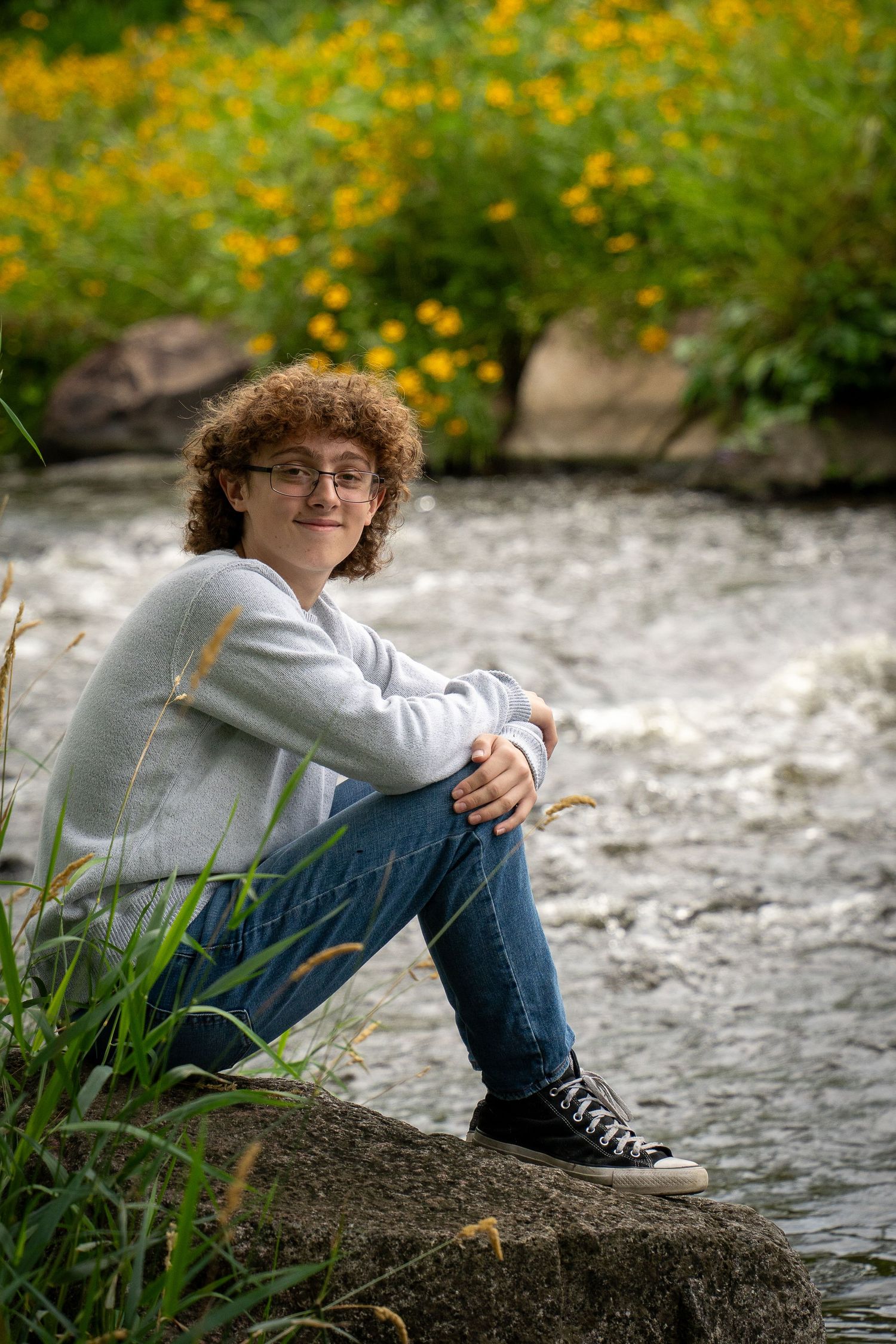 Wisconsin Senior and Portrait Photographer - Boy sitting on a rock on river smiling in Wisconsin during a summer senior portrait session.