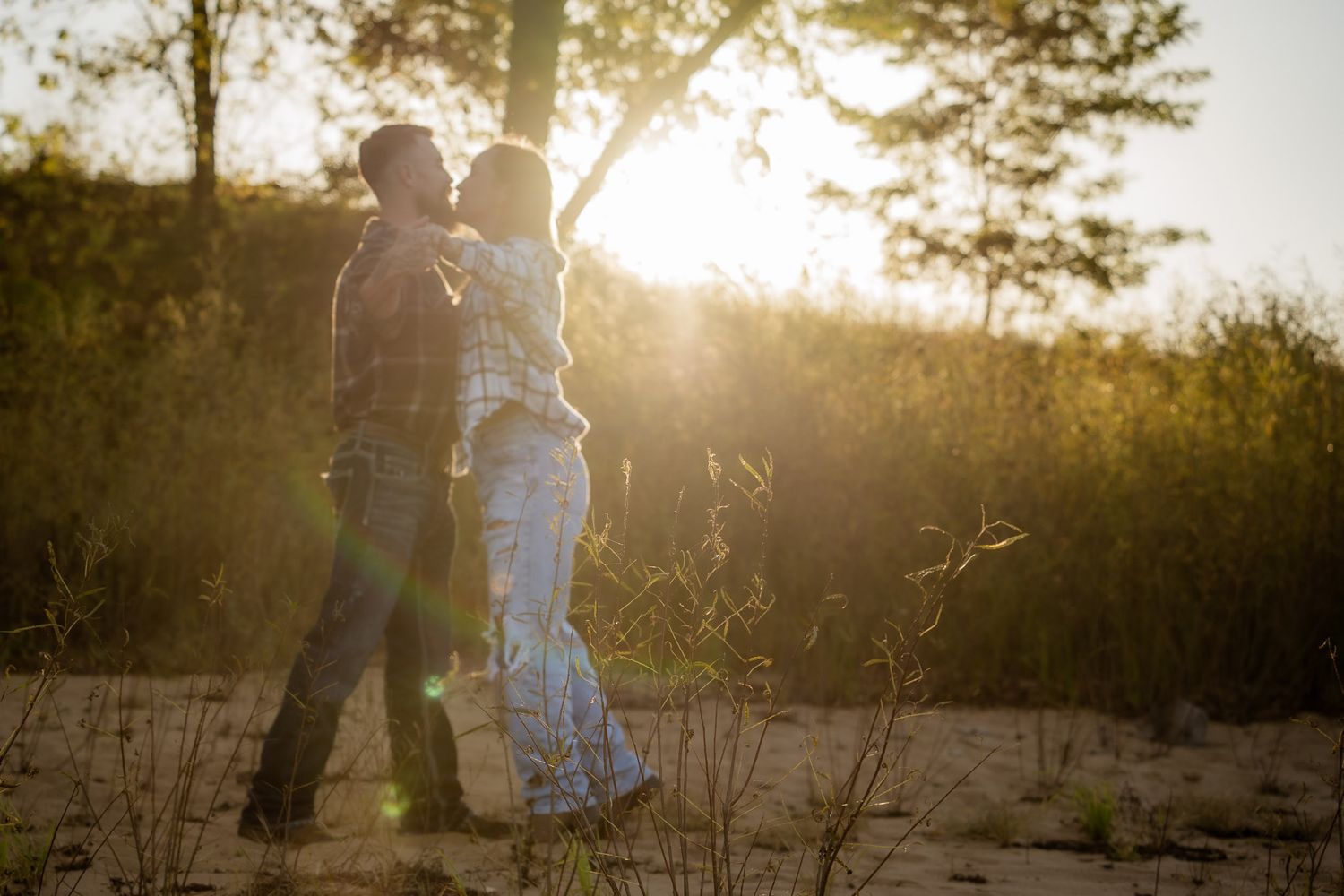 Wisconsin Couple and Engagement Photographer - Couple kissing on a beach in fall during an engagement session in Wisconsin during sunset.