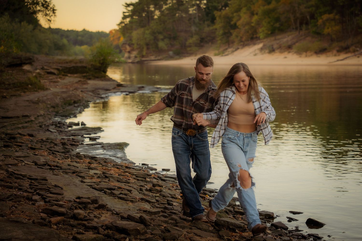 Wisconsin Couple and Engagement Photographer - Couple walking on riverbank in fall during engagement session in Wisconsin during sunset.